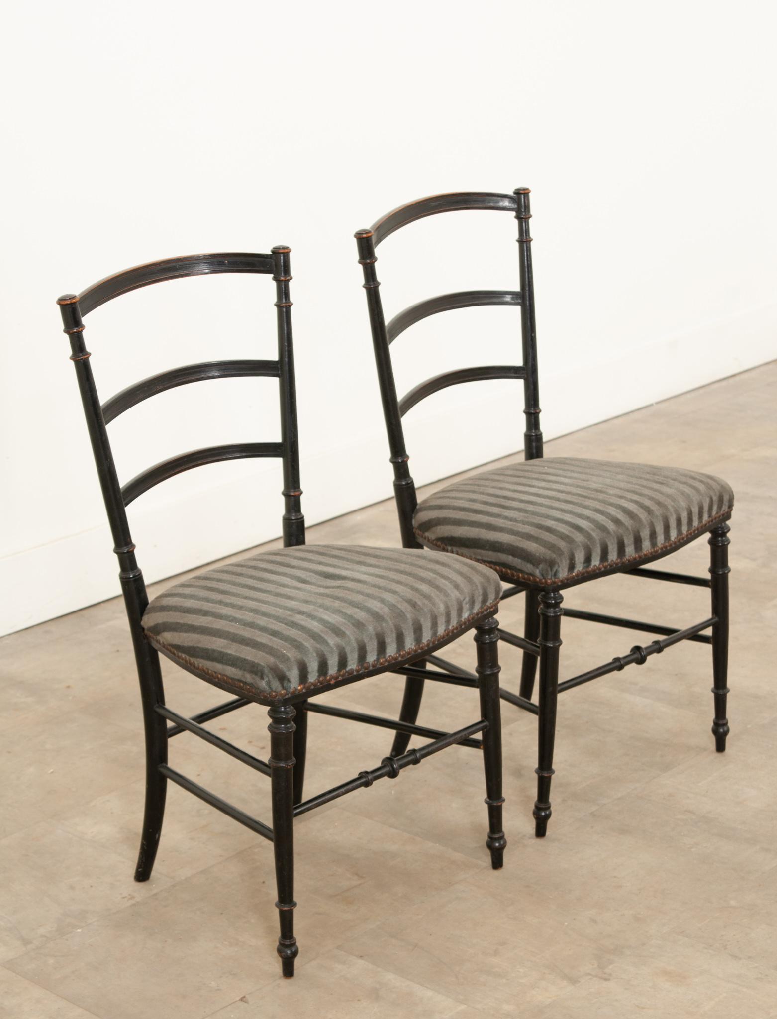 This is a superb pair of  Napoleon III era opera chairs that date to the 1850s. These exceptional, ebonized chairs feature excellently patinated ladder back supports with comfortable and tightly upholstered seats on well supported legs. The chairs