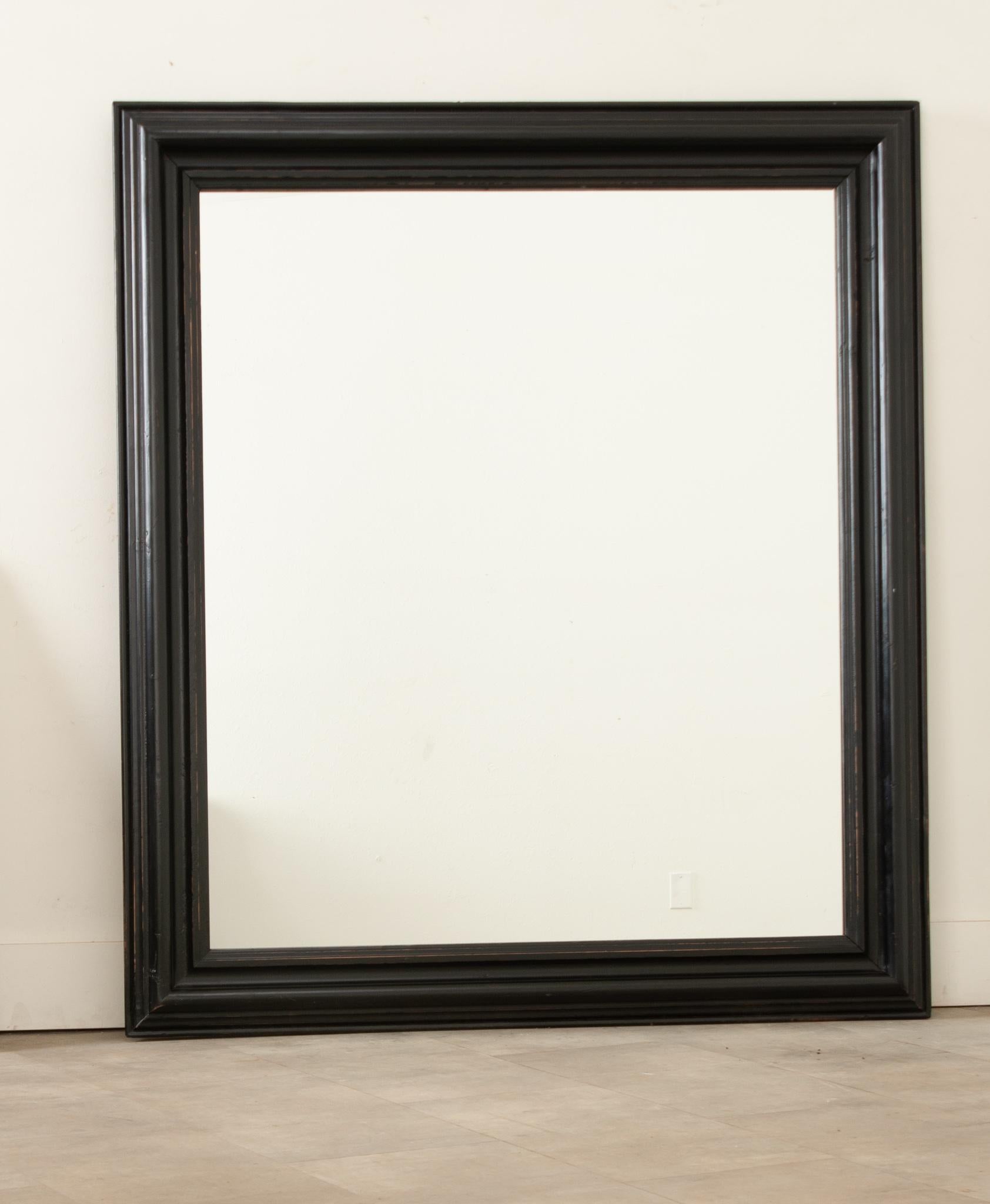 A very fetching French late 19th century ebony symmetrical bistro mirror with original glass and an ogee frame. Dating circa 1870 this charming mirror has a lovely patina that pairs its clean lines with visual texture.  A perfect choice for both