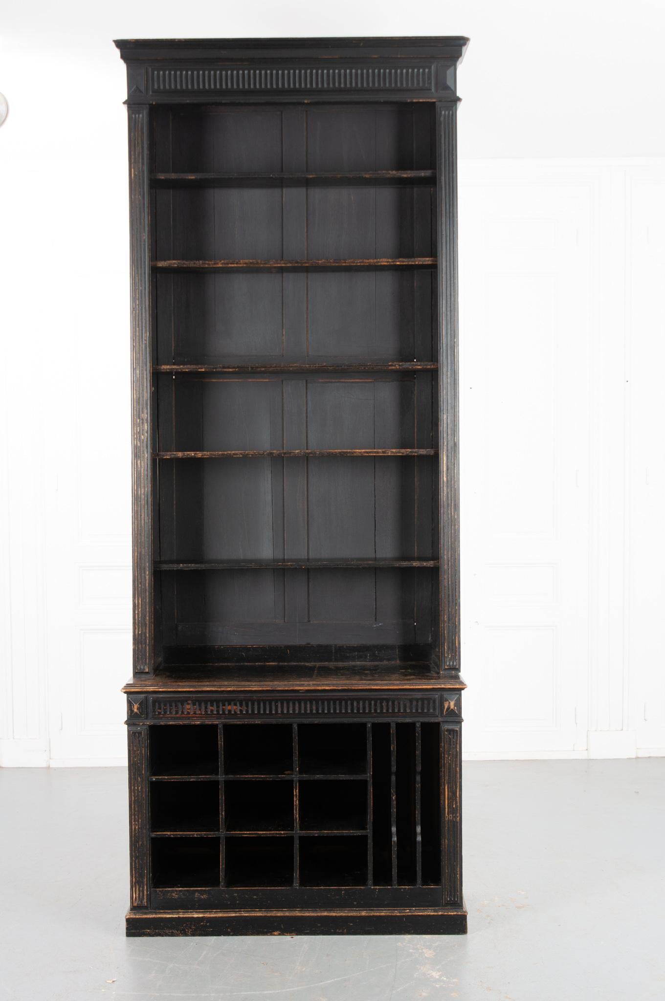 An impressively tall bookcase from 19th century France. A wonderfully aged ebony finish gives the whole a great patina! The top houses five adjustable shelves and measures 10” in depth. Fluted carvings on the top and shoulders match those found on