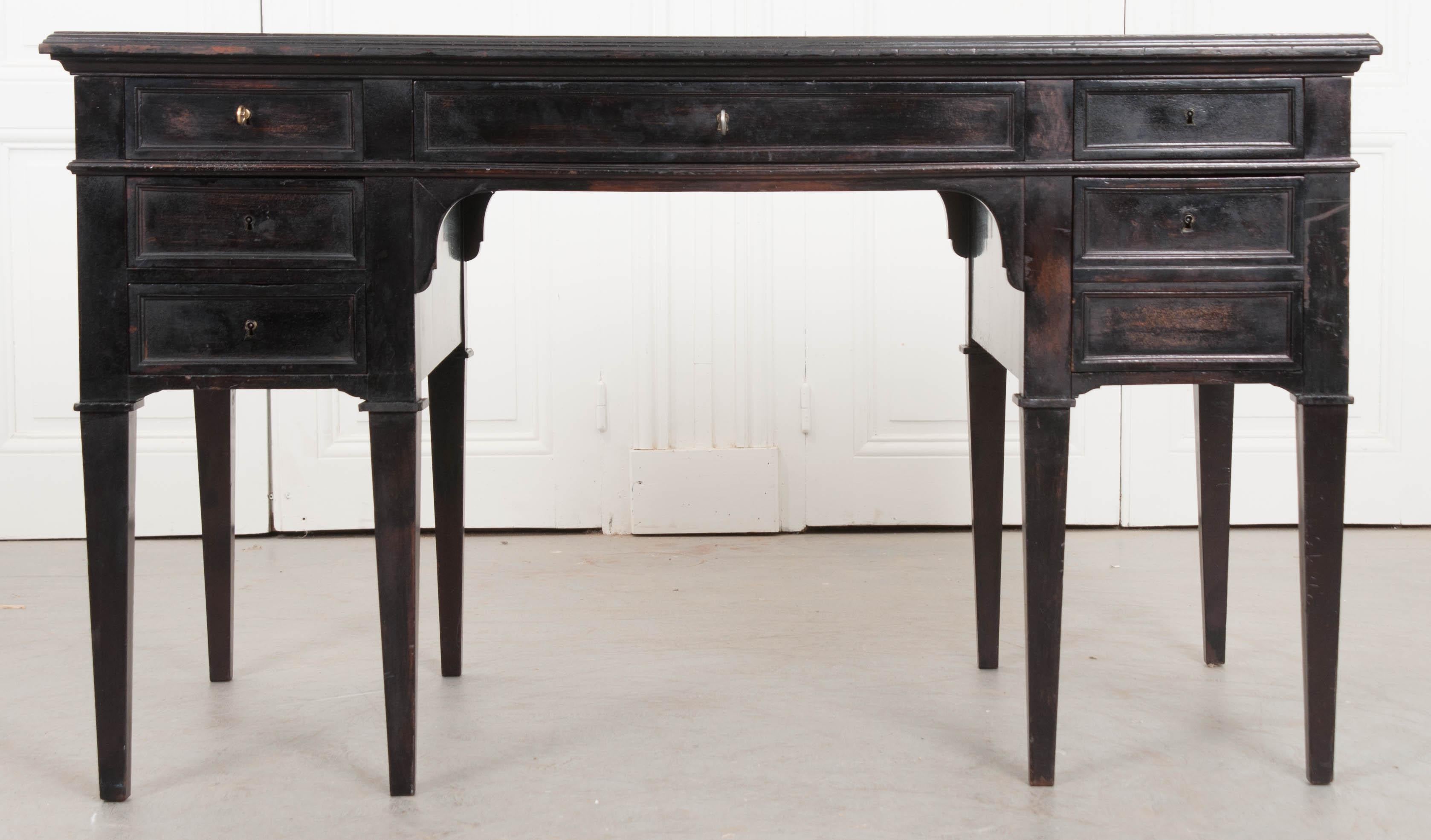 An elegant and refined French Directoire-style ebonized mahogany desk, c. 1800's, with inset tanned-and-tooled leather blotter and slide-out writing surfaces on each side that have richly deepened in color over time. Although it appears to have