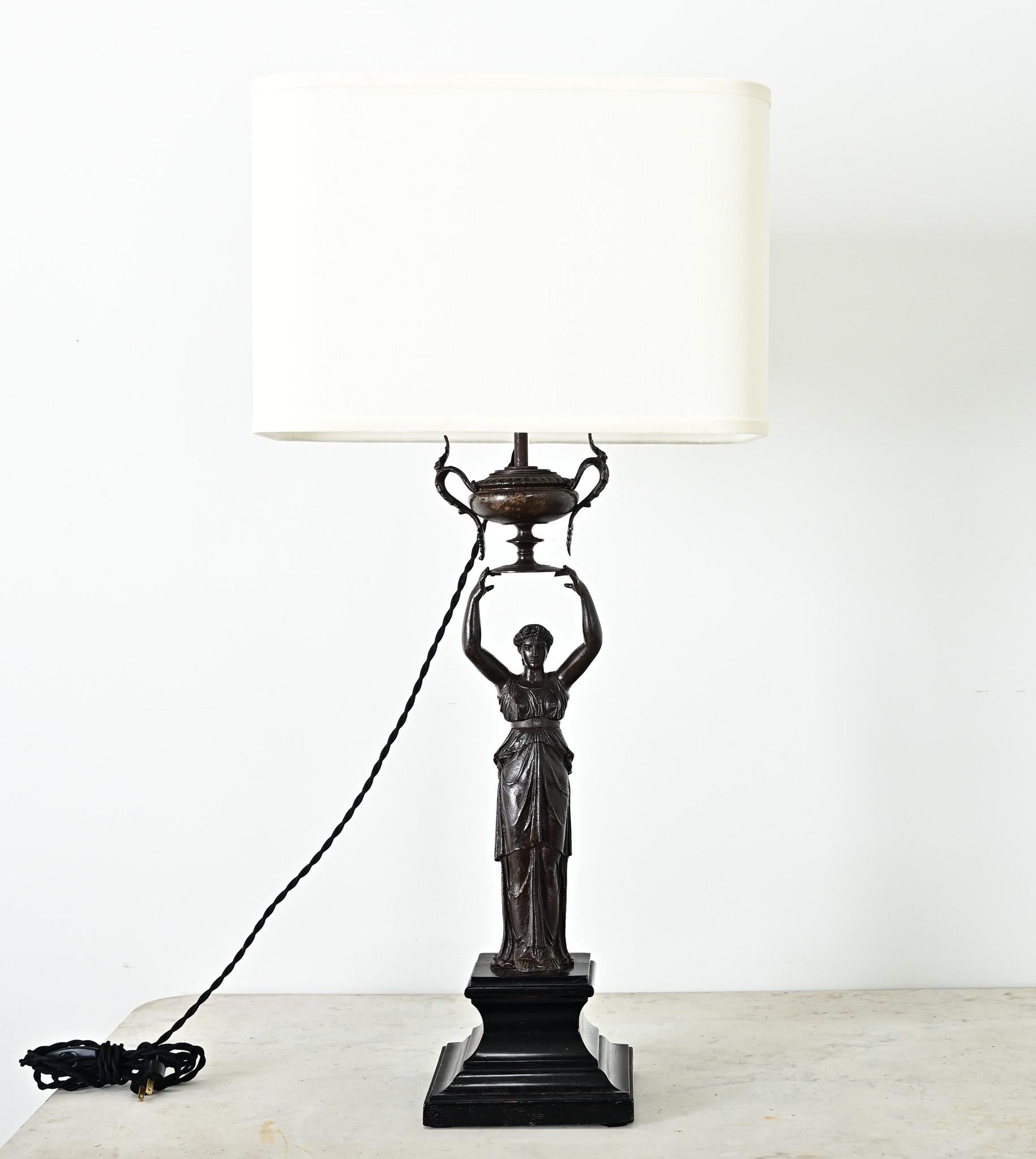 Lámpara de sobremesa francesa de bronce fundido del siglo XIX, estilo Imperio, con pantalla de lino nueva, convertida de gas a eléctrica. Esta importante luminaria neoclásica tiene por base una figura femenina grecorromana, que eleva sobre su cabeza