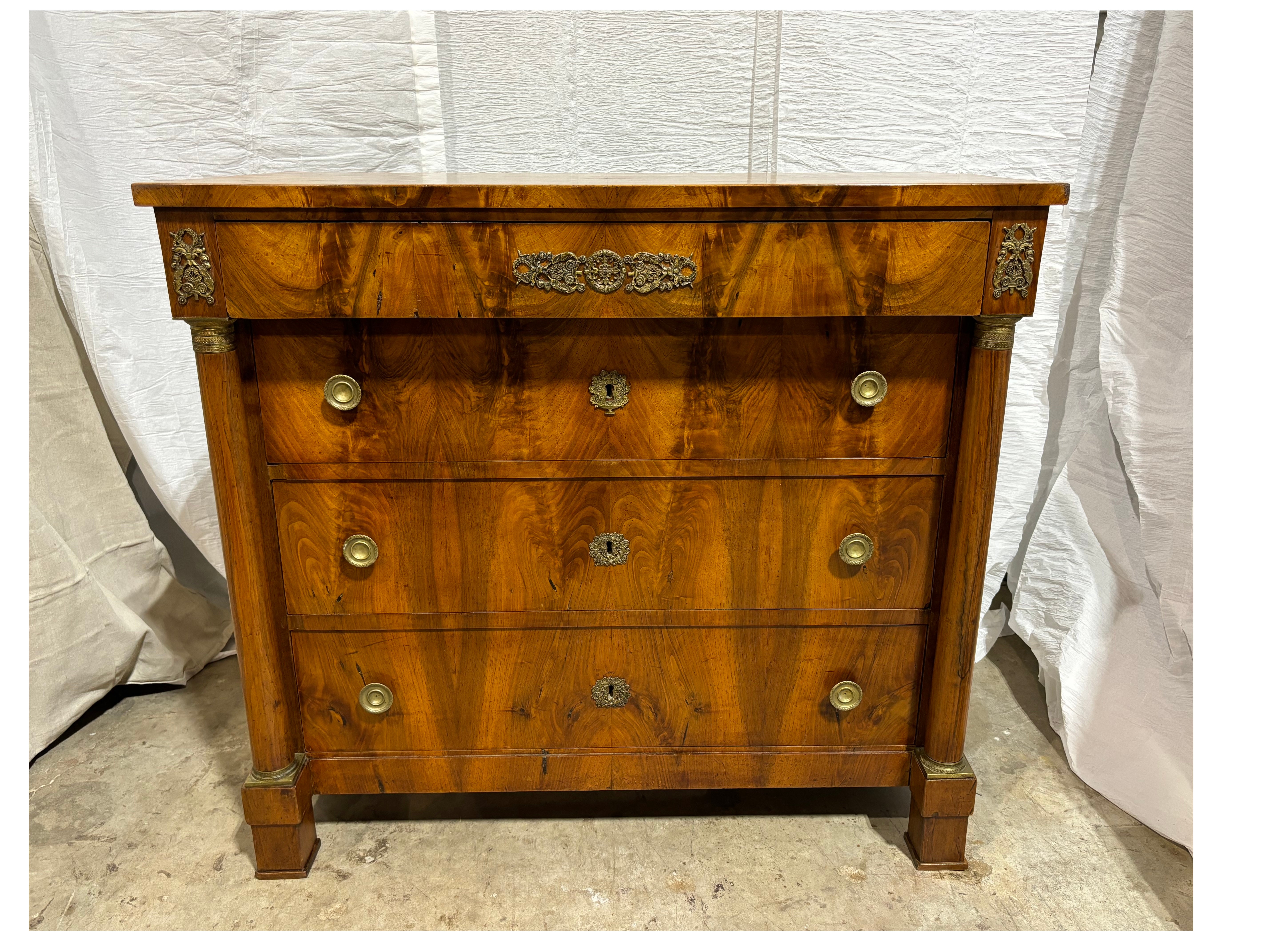 Cette magnifique commode Empire présente un magnifique flammage de noyer avec quelques ornements de bronze sur le tiroir supérieur.