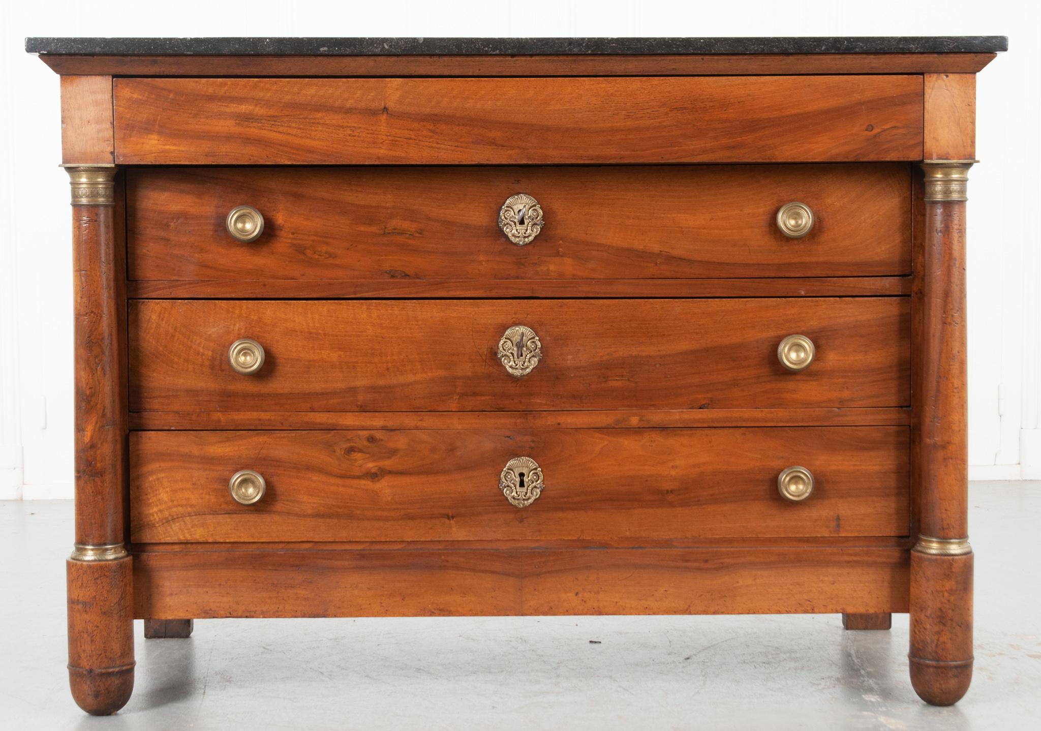 This is a fine French Empire style commode made of solid walnut. Topped by a beautiful piece of black marble with fascinating fossil inclusions, the body is made of solid walnut. A hidden drawer without hardware, sits flush at the top of the