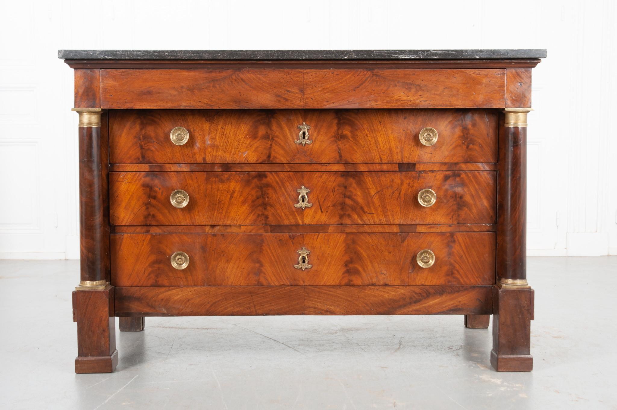 Four total drawers compose this dignified Empirically-styled mahogany commode. This case piece is topped in black / charcoal-colored fossil marble that, along with the body, has patinated wonderfully over the decades. A hidden drawer, free of any