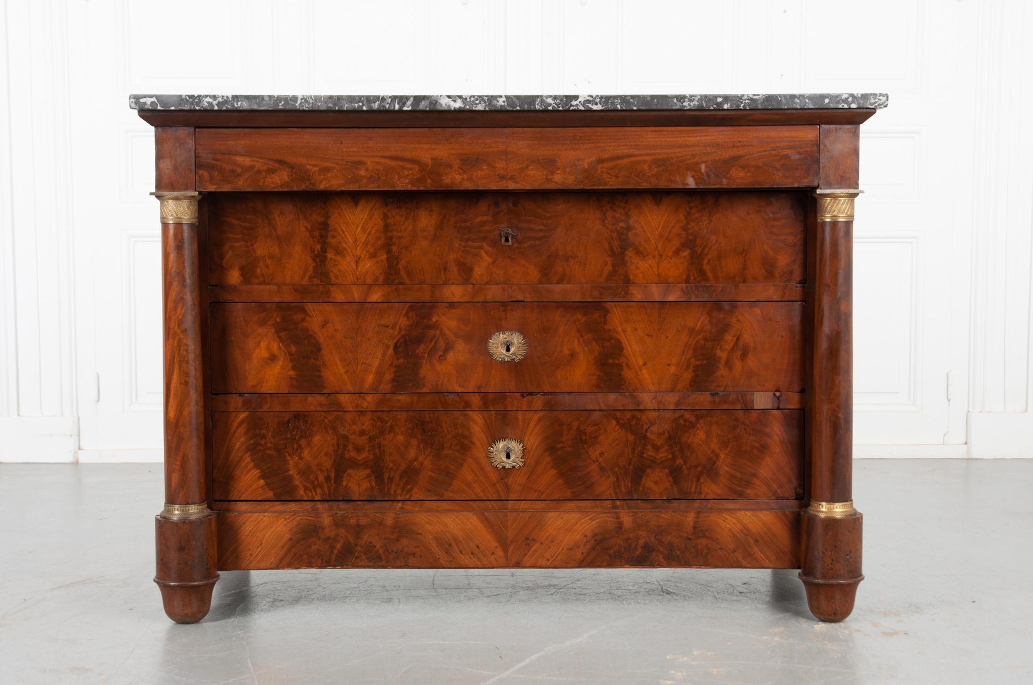 A fabulous Empire style commode from 19th century France, circa 1830. The stunning gray and white marble top with rounded front corners is in great antique condition. A hidden drawer within the apron allows for extra storage space. Three drawers