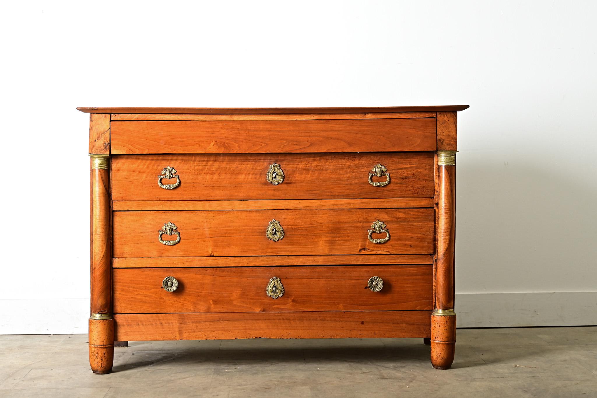 Una robusta commode francese in noce Impero del XIX secolo. Le tavole superiori sono lisce, disposte a quadrato per incorniciare l'ampia tavola centrale che esprime le sue venature naturali con una patina scura. Il fregio sporgente è un cassetto