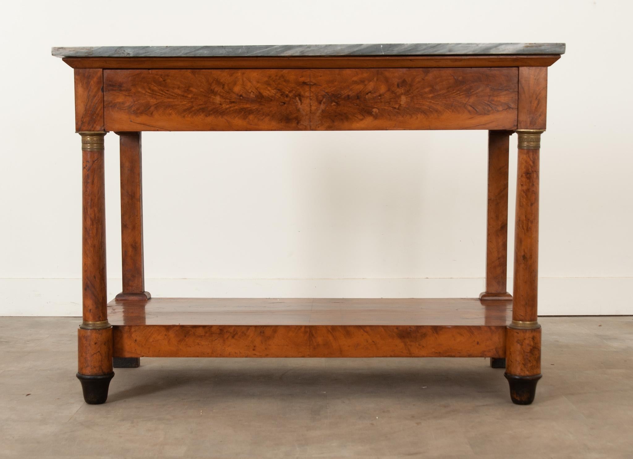 This French 19th Century bookmatched flame mahogany console has its original charcoal marble top that fits over the base. Column-form front legs support the top along with the console’s more restrained, finished linear rear legs. The front legs are