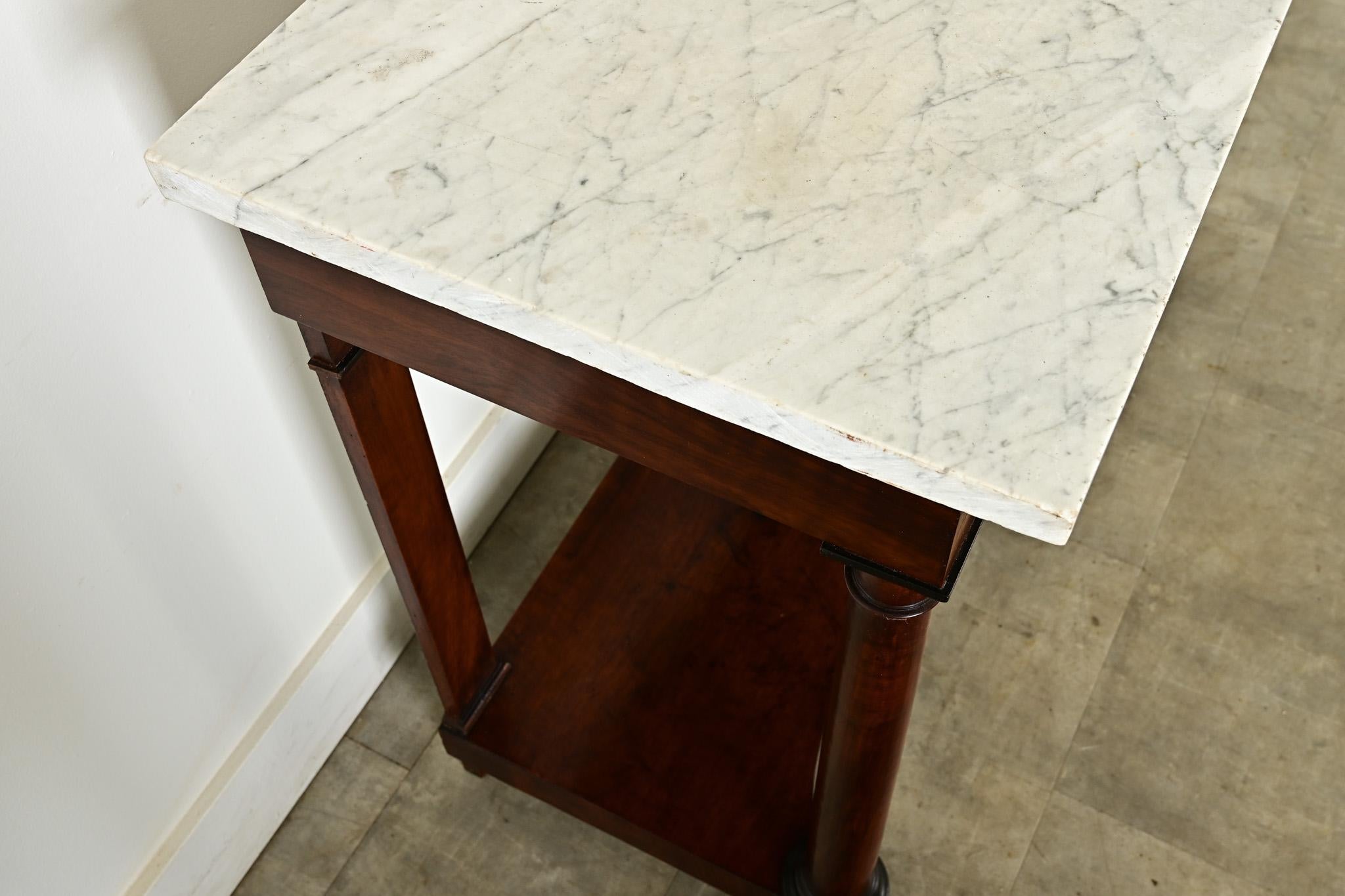 Consolle in mogano stile Impero del XIX secolo. Lo spesso piano in marmo di Carrara è in splendide condizioni d'epoca e presenta interessanti venature grigie che creano un piacevole contrasto con le linee ordinate e pulite della base. La parte