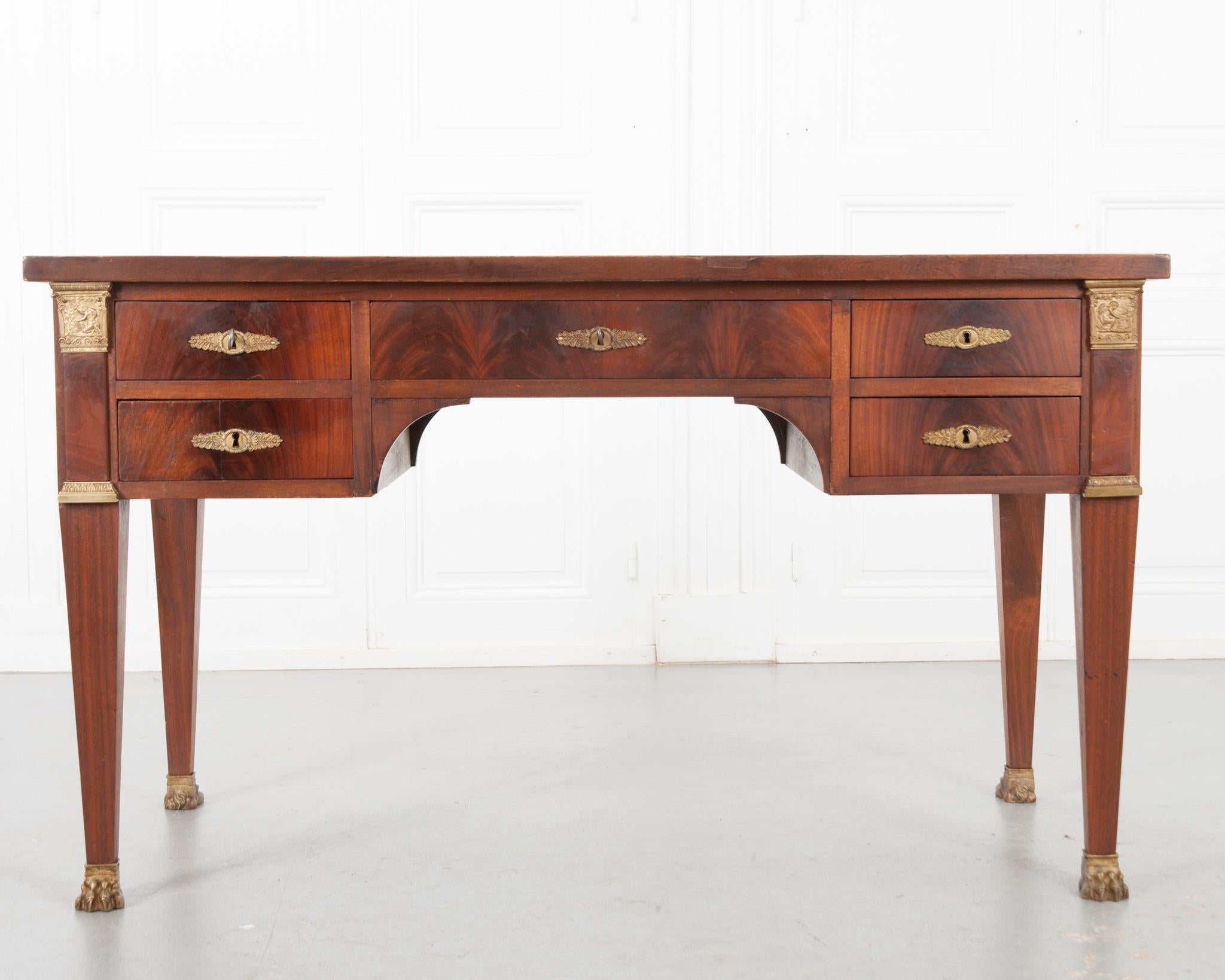 A handsome Empire desk from 19th century France. Made from a beautiful mahogany that’s been cleaned and polished to reveal the vibrant grain. The top is inset with the original worn caramel toned leather, detailed with gold tooling around the