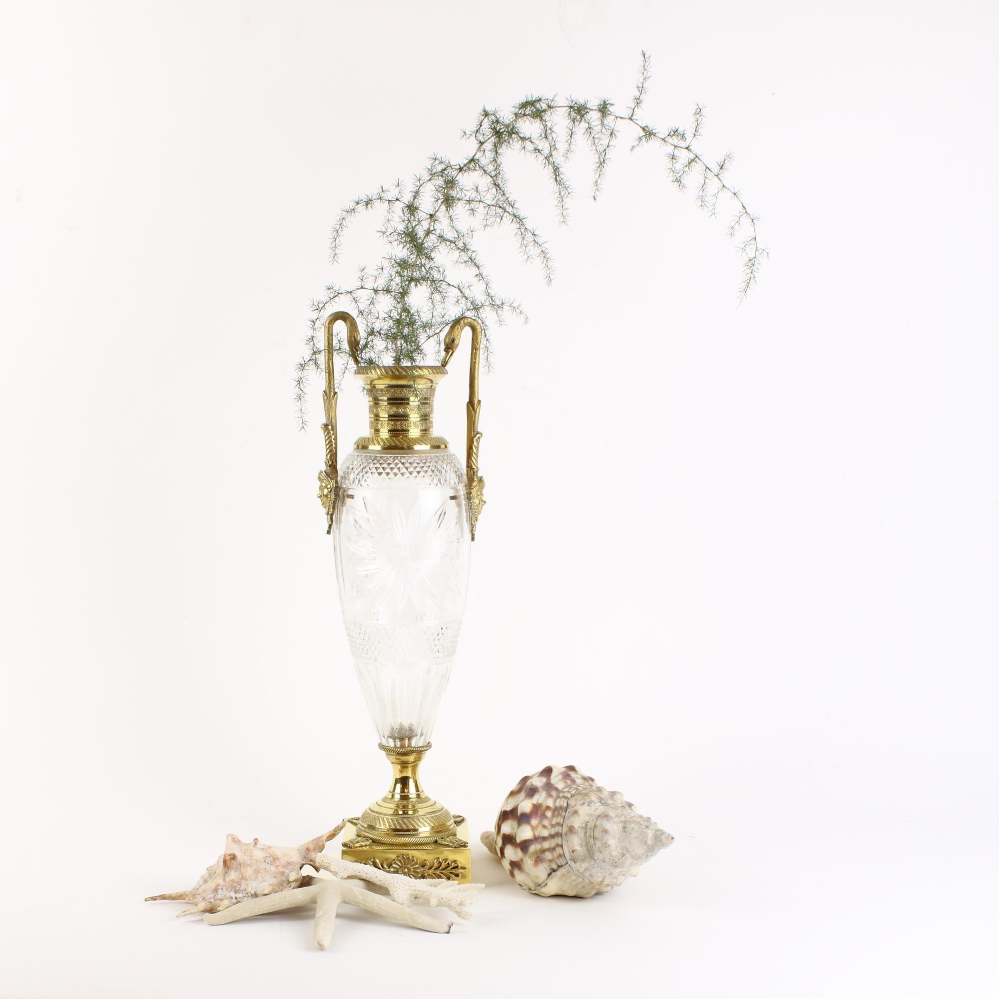 French 19th century empire gilt bronze and cut crystal glass amphora vase

A slender ovoid crystal glass vase standing on a round gilt bronze foot with a rectangular plinth which is decorated at all corners with the French Imperial eagle. Two