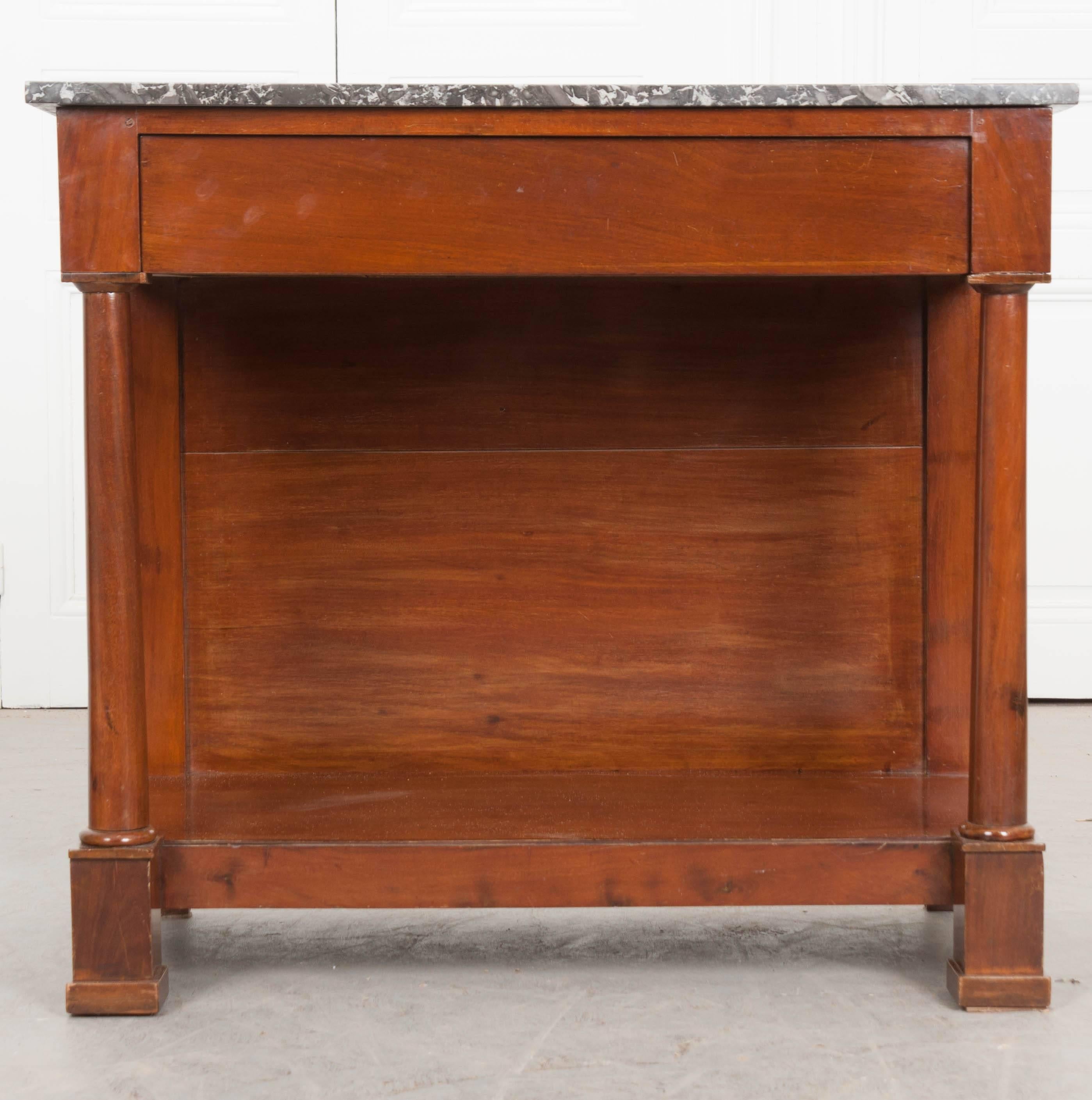 A French 19th century mahogany console with Empirical style and marble top. The gray marble top is in wonderful antique condition, with the front and sides being finished. The apron houses a hidden drawer, providing out-of-sight storage. The top is
