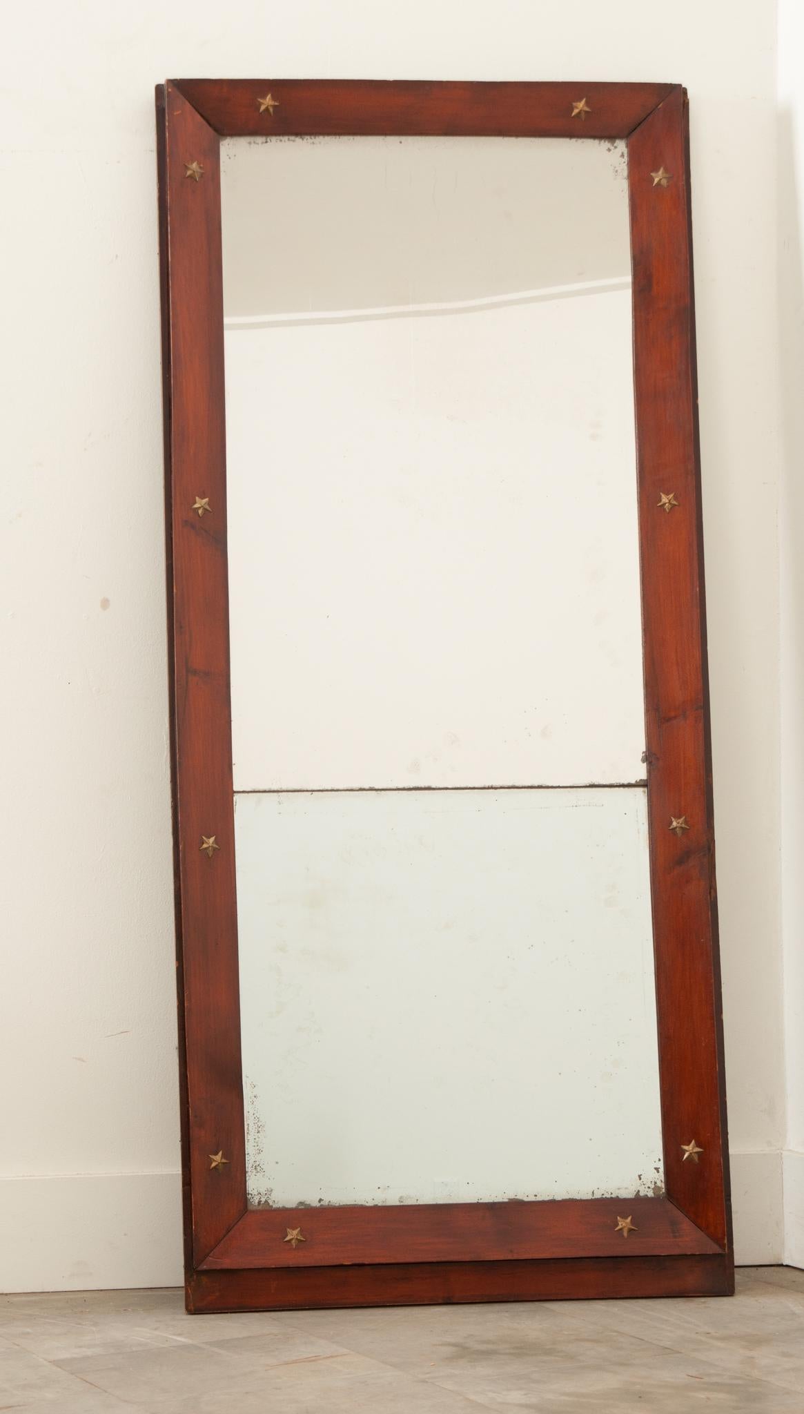 A courtly, Empire mirror from France with its original mirror plate. The frame is made of beveled mahogany decorated with gilt bronze stars, a motif commonly found throughout the Empire style. Dating circa 1860, this mirror is truly striking, as the