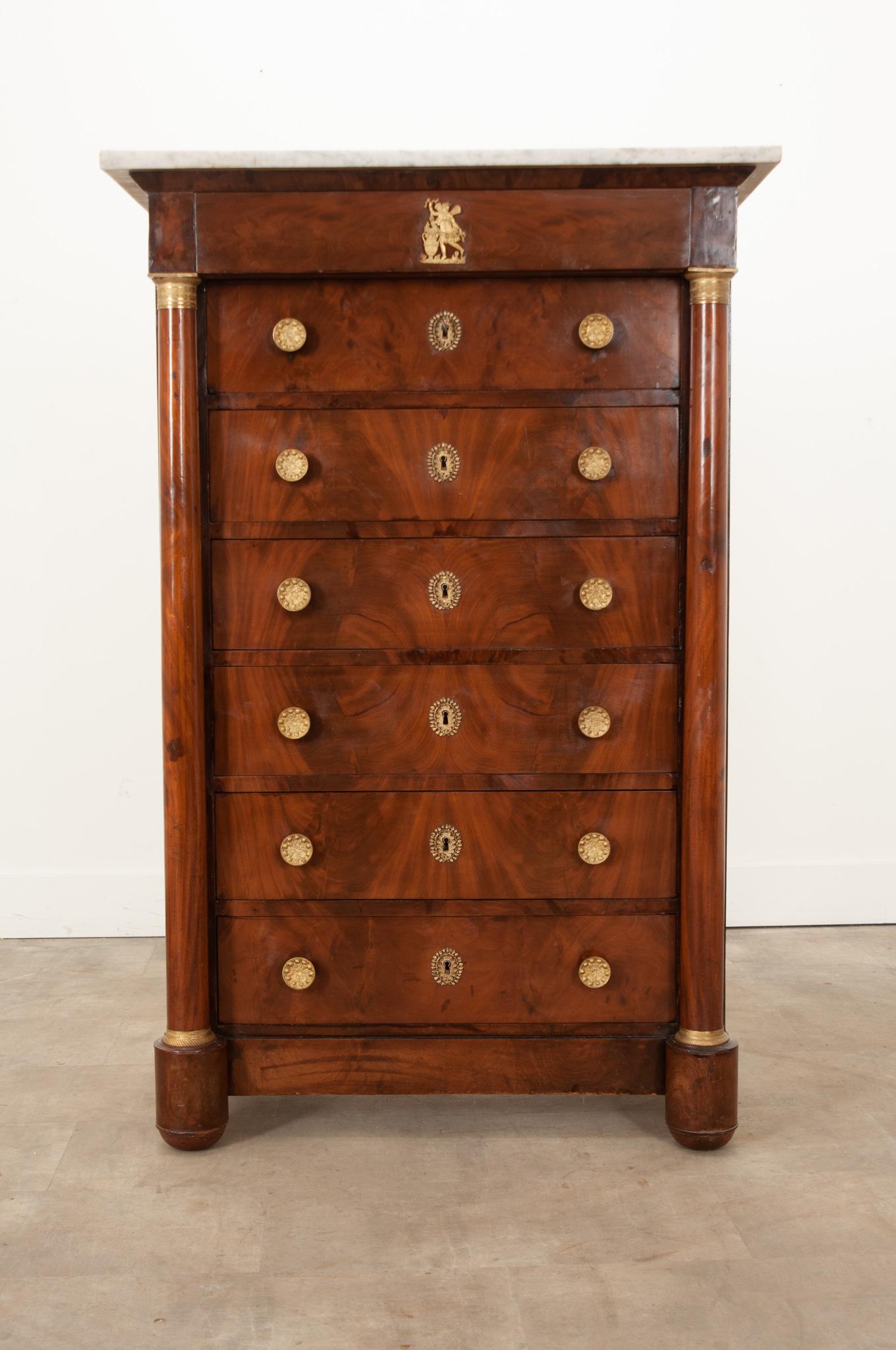 A 19th century French Empire mahogany semainier featuring artful neoclassical hardware. Hand-crafted in France circa 1810, this semainier is fitted with seven drawers to provide a drawer of clothing or lingerie for every day of the week. A beautiful
