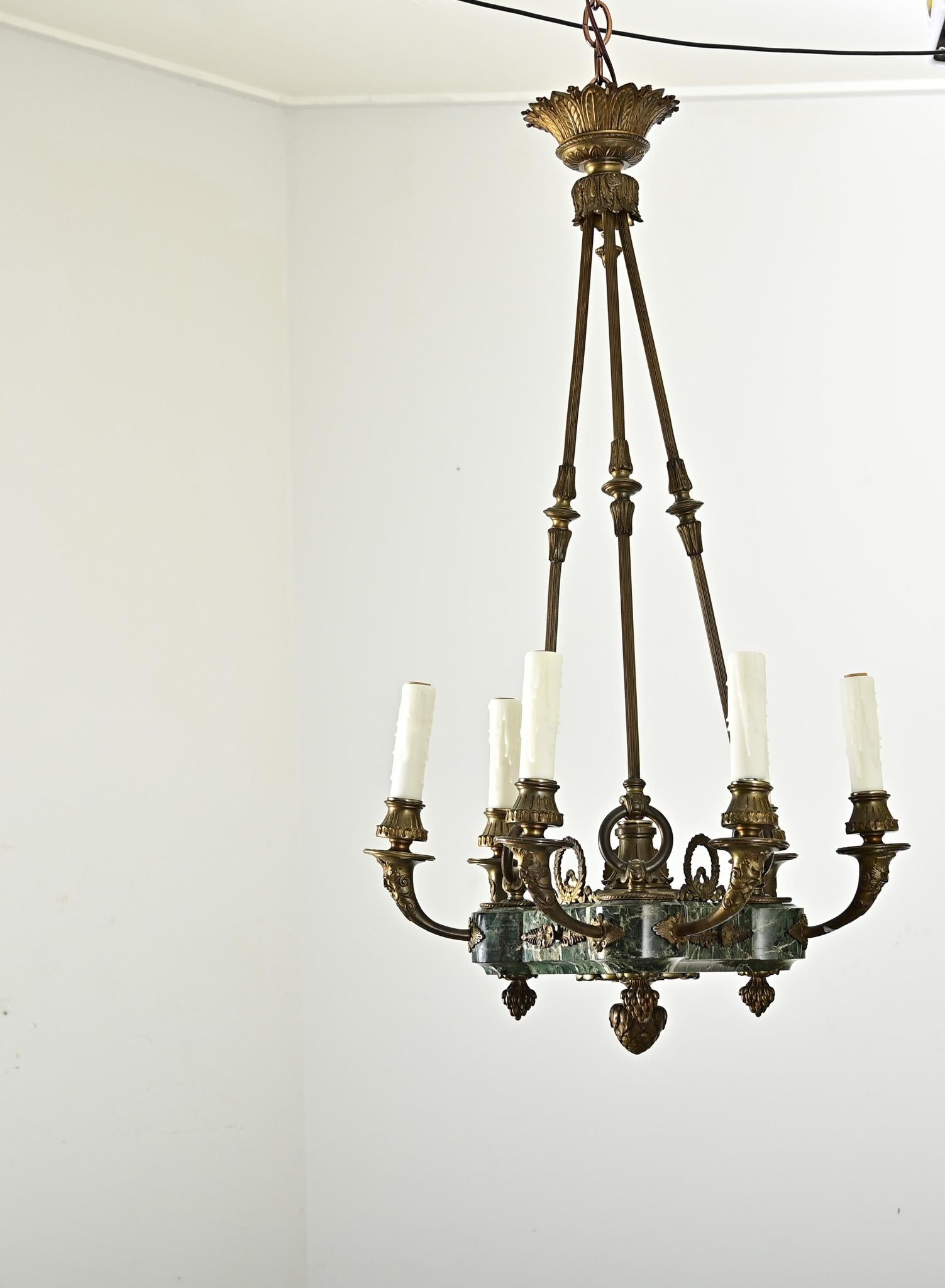 Un lampadario dell'Impero francese, unico nel suo genere perché ricavato da un blocco massiccio di marmo verde, decorato con applicazioni e finali in bronzo dorato su ogni superficie per proiettare la sfacciata grandezza dell'epoca. Tre aste di