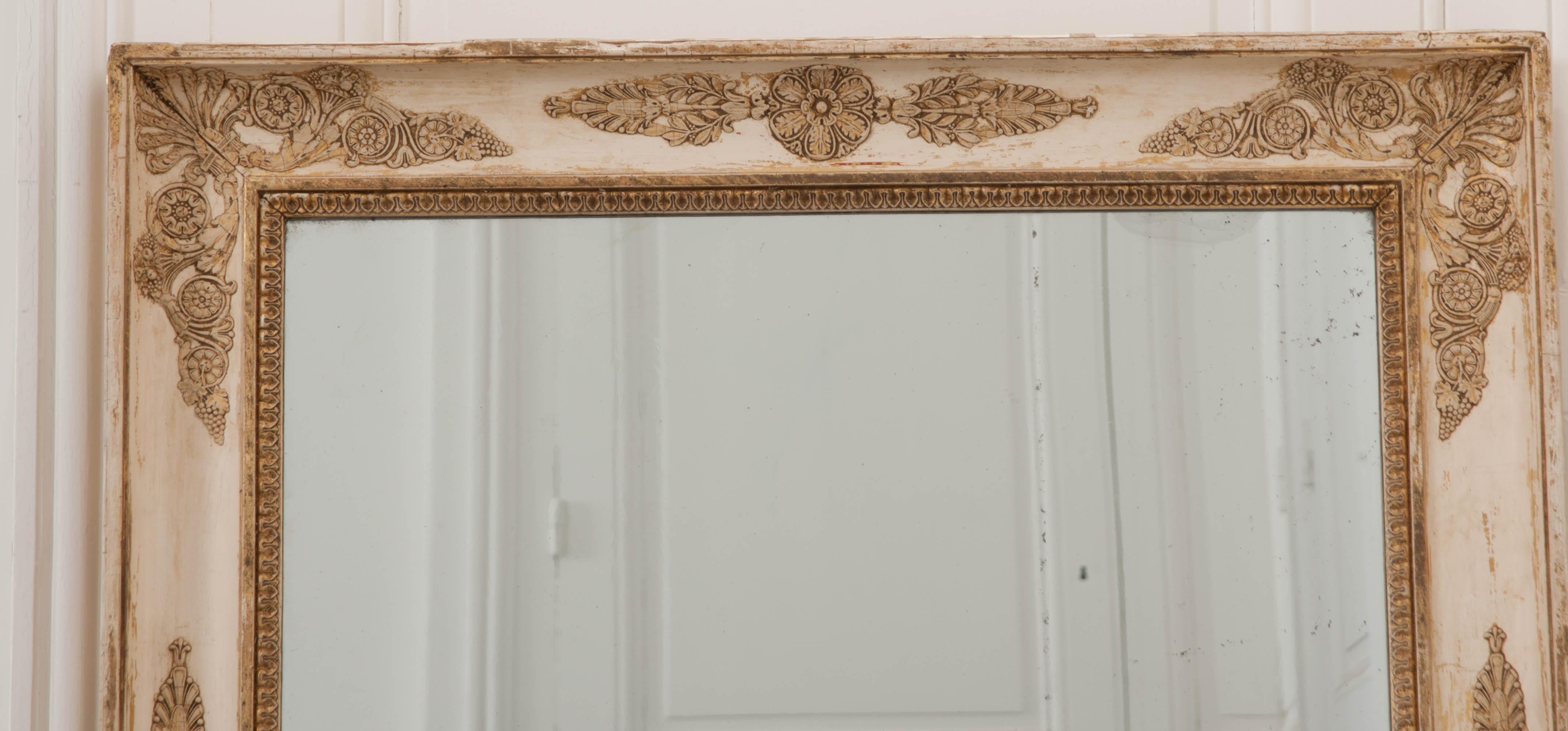A fabulous Empirically styled rectilinear mirror from 1870s France. The mirror’s frame has lost much of its original gold gilt, but has retained all of its regal beauty. Detailed motifs in grape, rosette, scrolled acanthus and palm styles embellish
