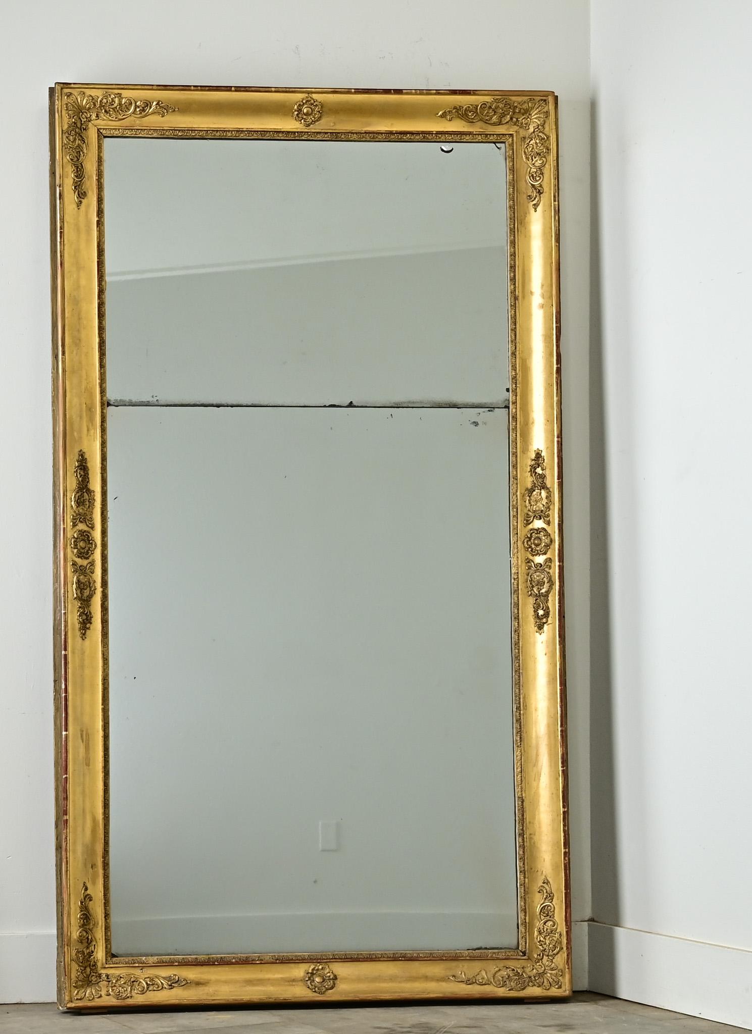 Questo specchio da camino dell'Impero francese (1800 circa) mostra una calcolata moderazione nella decorazione della superficie; la modanatura dorata è in gran parte semplice e liscia, con intagli di piume e foglie posti a intervalli regolari lungo
