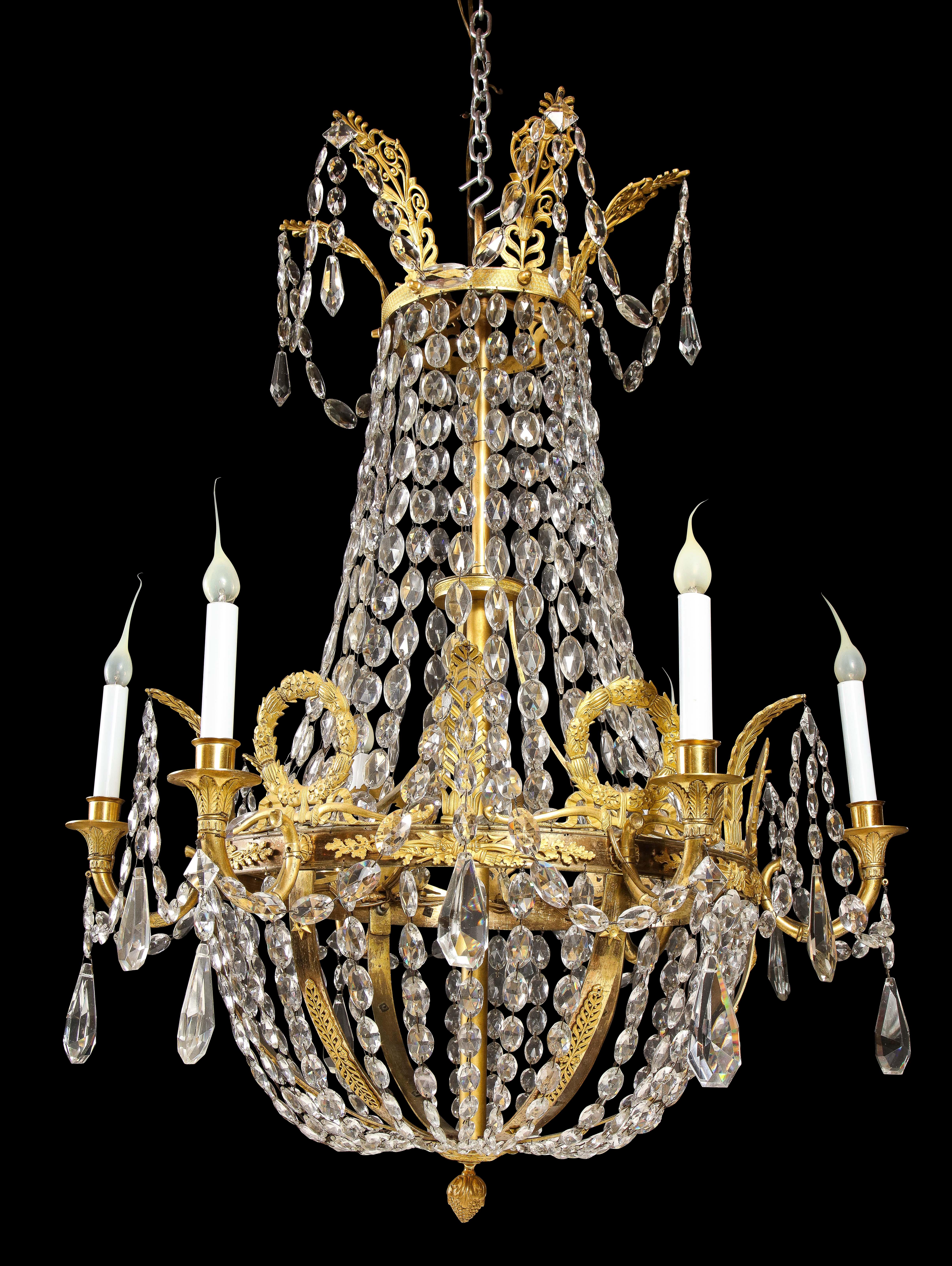 Questo importante lampadario Impero francese, risalente al XIX secolo, presenta una cornice in bronzo dorato ornata da motivi neoclassici. La struttura in ormolu comprende corone e foglie d'acanto finemente fuse, caratteristiche dell'estetica