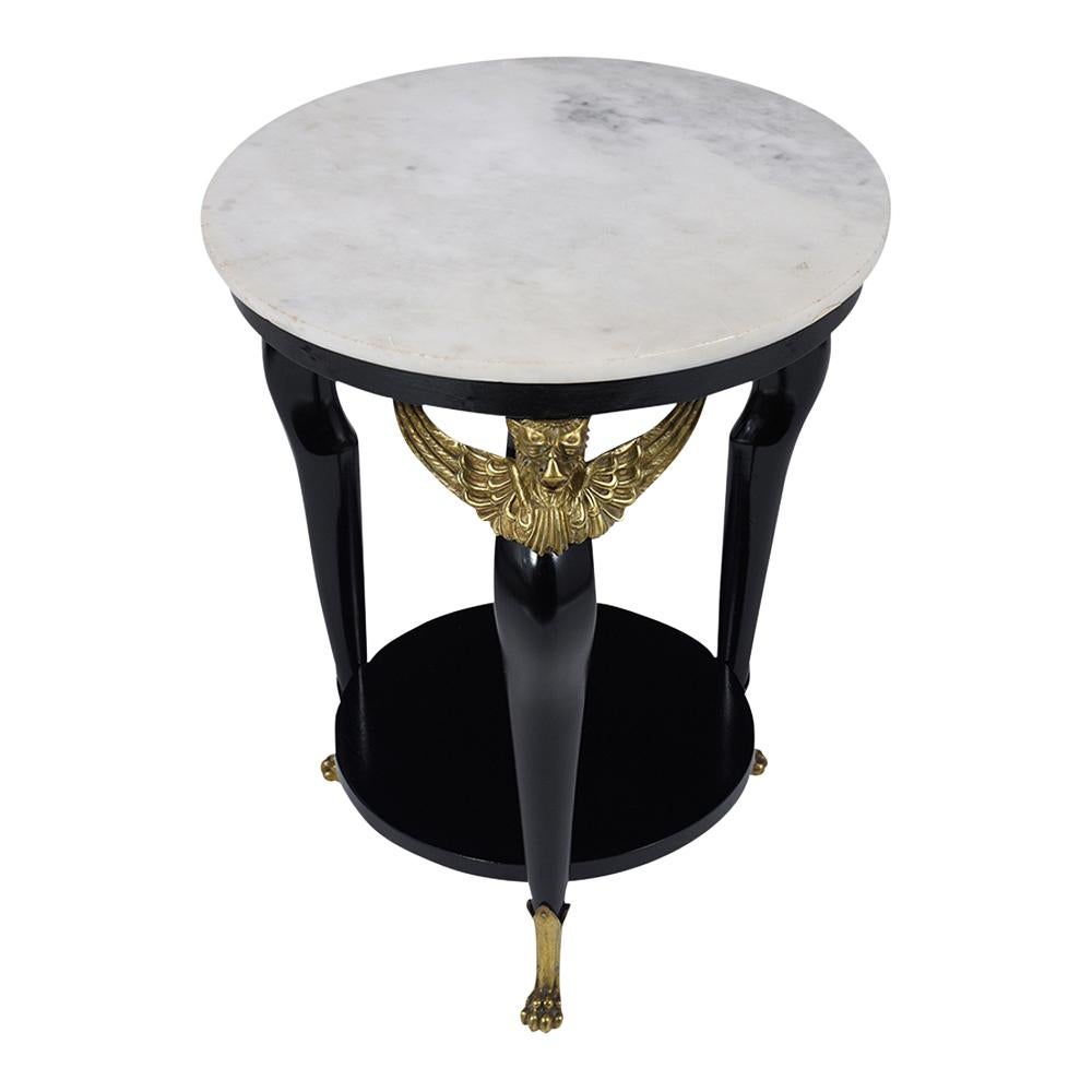 This is a lovely 1880s French Empire Round Side Table made out of mahogany wood, newly stained in deep black color with a lacquered finish. The end table comes with the original off-white marble top, brass decorations on the corners of the long