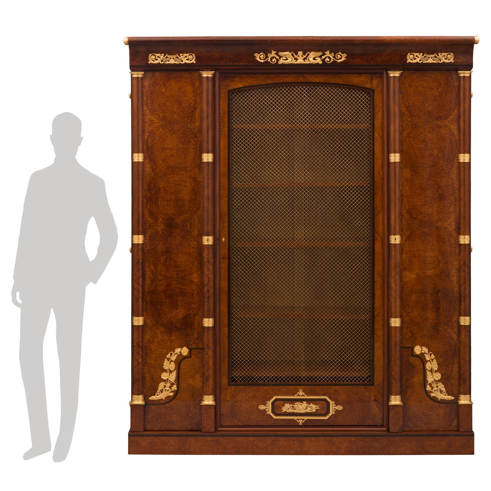 An impressive and high quality French 19th century Empire st. burl elm, ebony, tulipwood, and ormolu cabinet. The large scale three door cabinet is raised by a straight base with an elegant ebony band and two fine tulipwood fillets. The central door