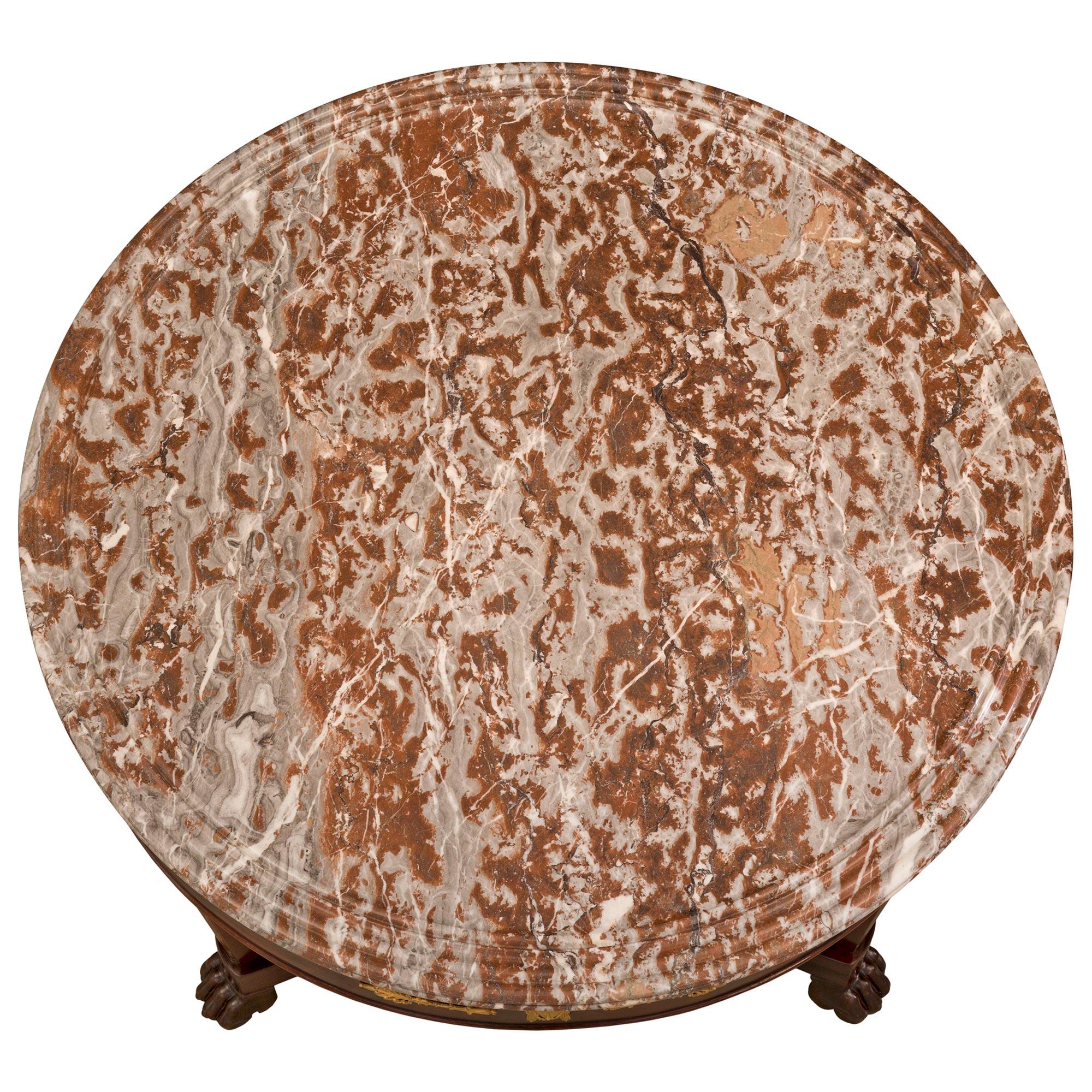 Ein sehr schöner französischer Empire-Tisch aus dem 19. Jahrhundert aus Mahagoni, Ormolu und Coquillier de Bilbao-Marmor. Der runde Tisch steht auf drei eleganten, quadratischen, spitz zulaufenden Beinen mit eindrucksvollen Tatzenfüßen und ist mit