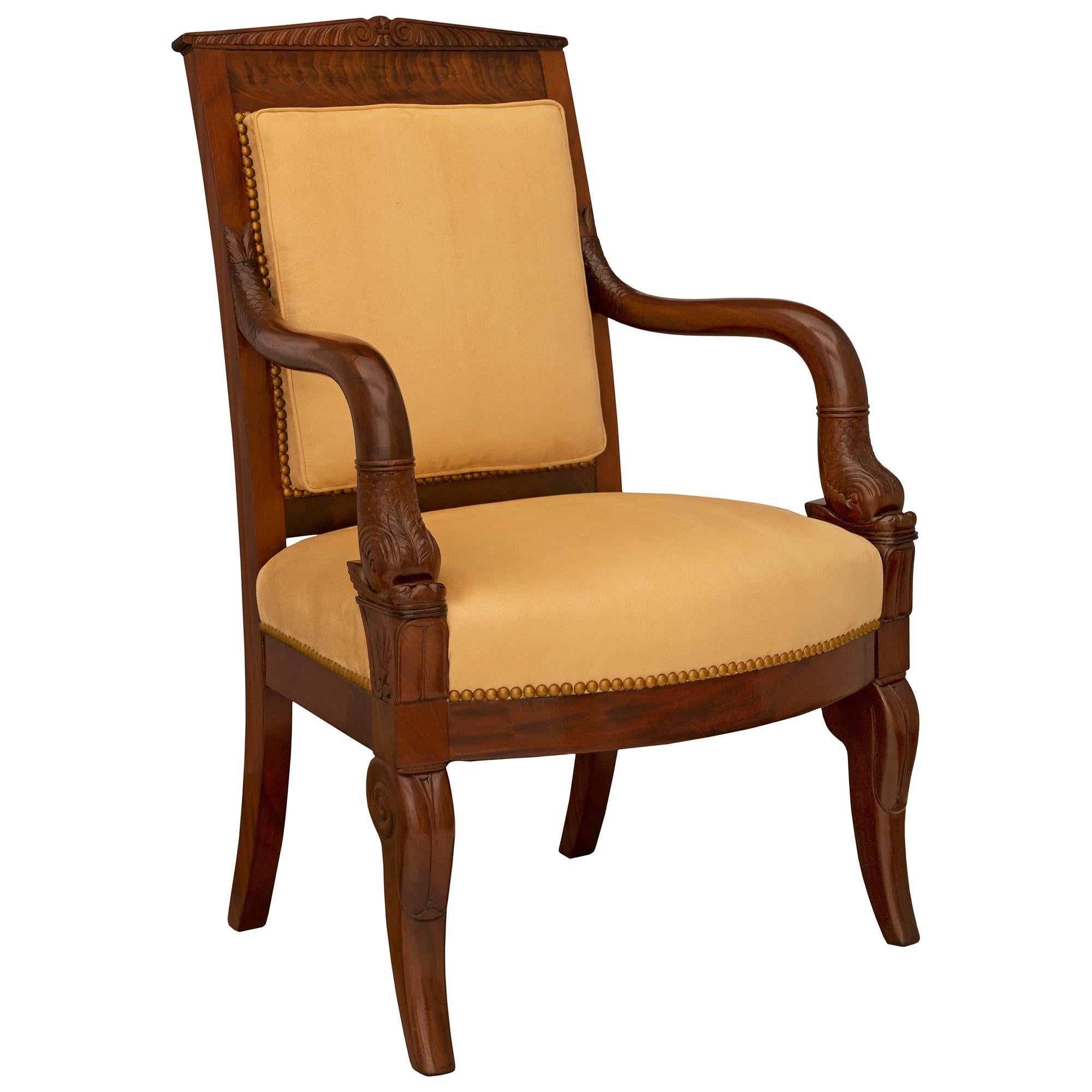 Magnifique fauteuil de bureau en acajou flammé de style Empire du XIXe siècle. Le fauteuil repose sur des pieds robustes, élégamment enroulés et finement sculptés à l'avant, et sur des pieds carrés légèrement incurvés à l'arrière. Chaque bras