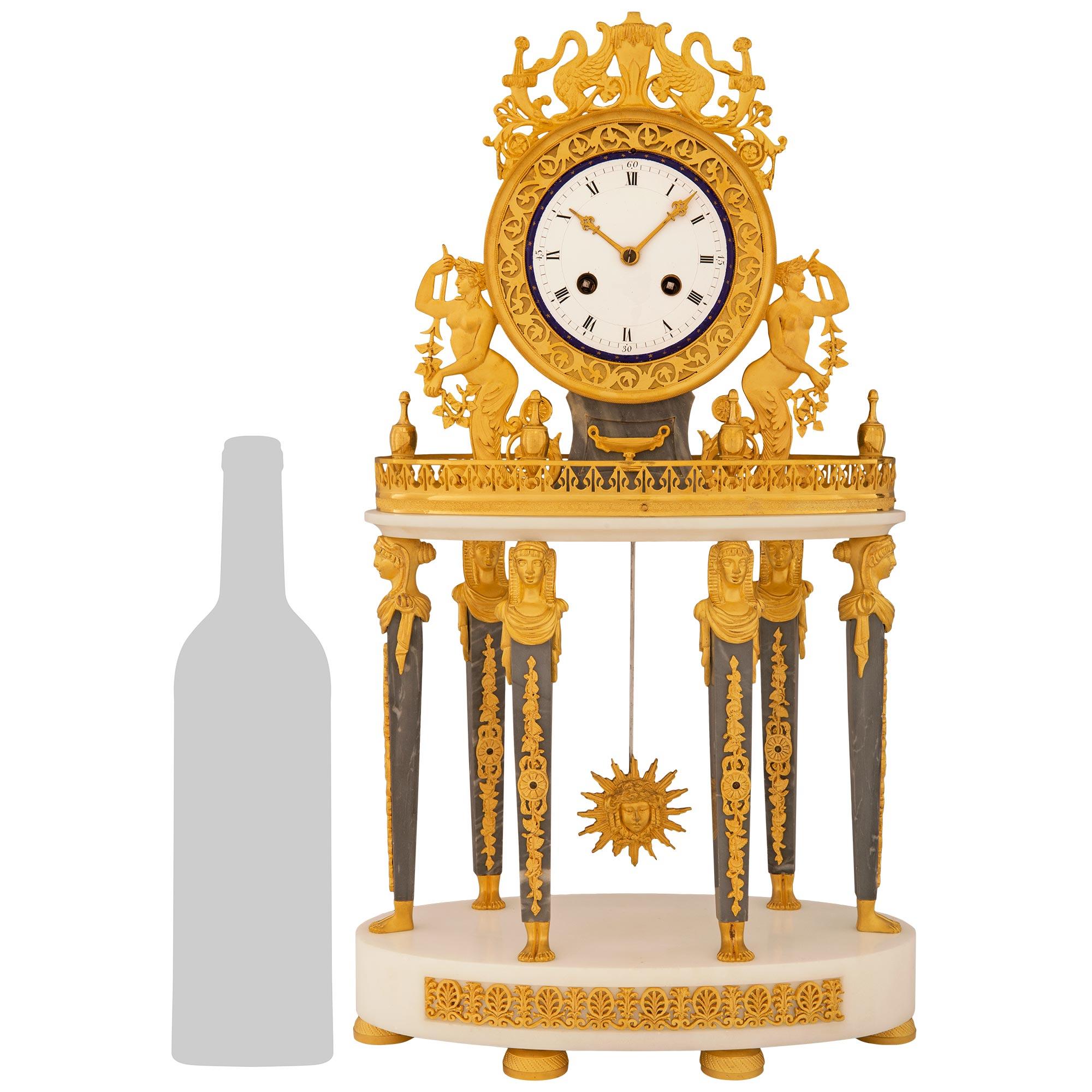 Eine atemberaubende und qualitativ hochwertige französische Empire-Uhr aus dem 19. Jahrhundert in St. Anne Gris, weißem Carrara-Marmor und Ormolu. Diese schöne Uhr steht auf einem runden Sockel aus weißem Carrara-Marmor mit einem durchbrochenen,