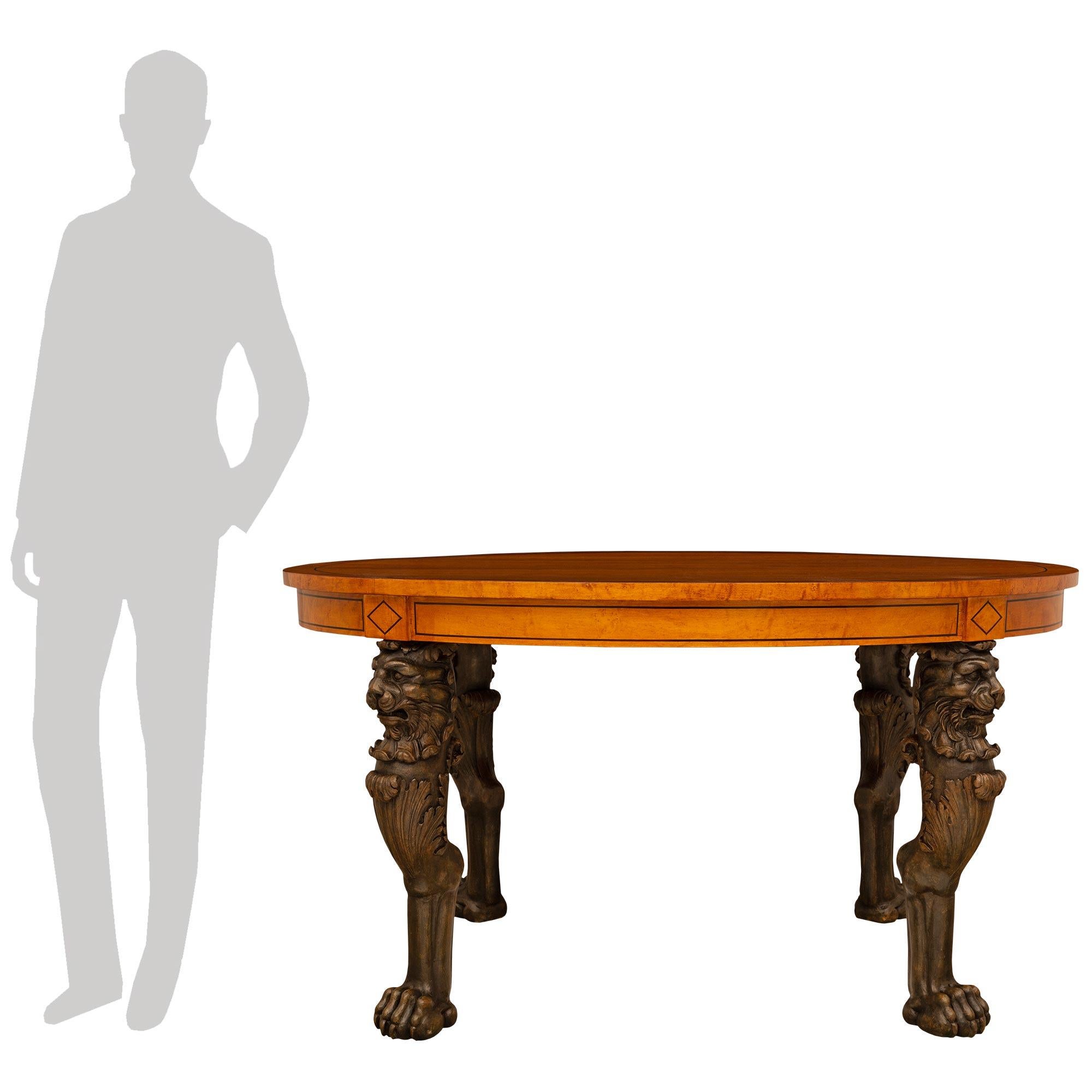 A finely detailed French 19th century Empire st. Lemon and patinated wood center table. This very unique oval table is raised by four statement making legs displaying large scale paw feet leading to a scrolled acanthus leaf below a handsome lion's