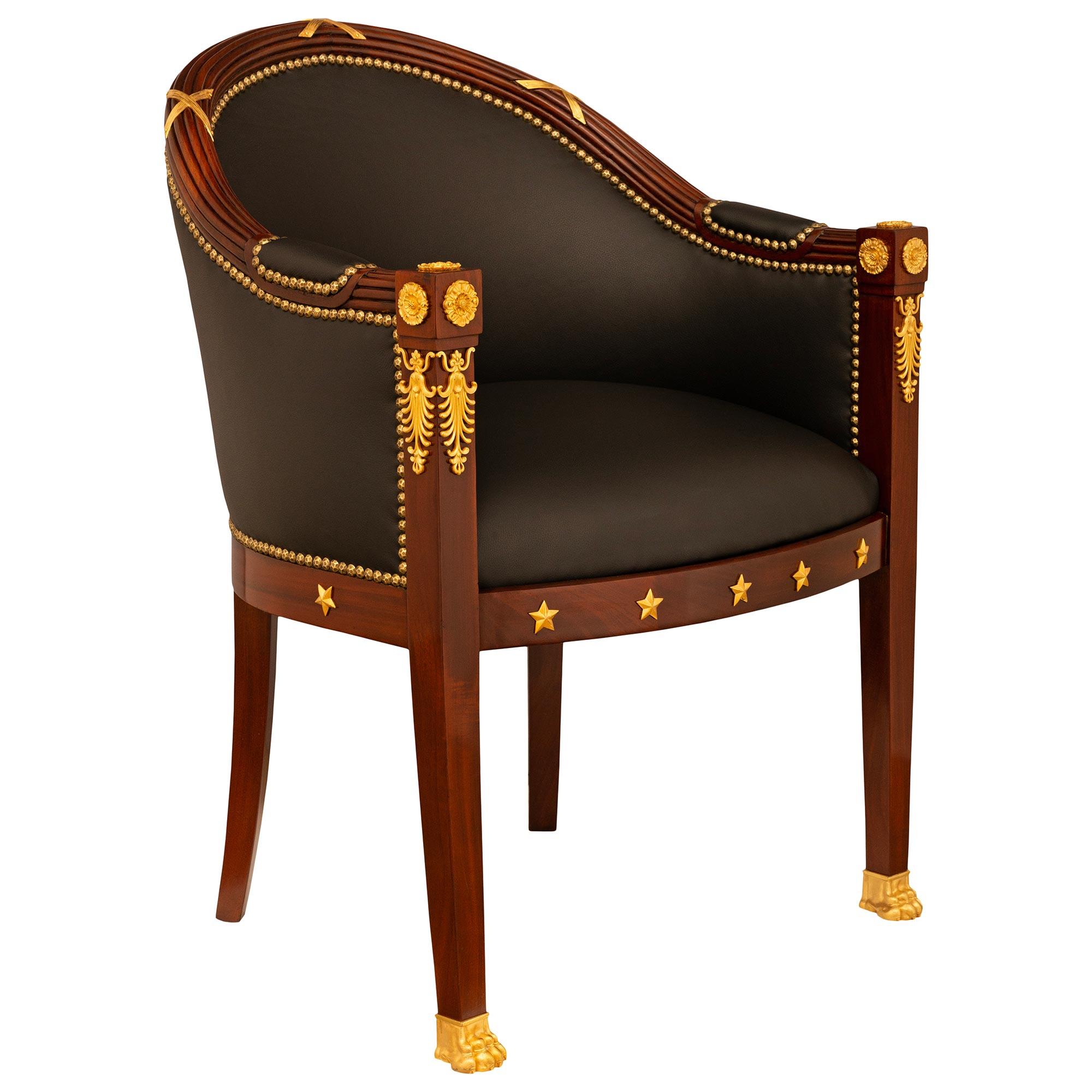 Magnifique fauteuil Empire du XIXe siècle en acajou et bronze doré. Le fauteuil repose sur quatre pieds carrés et légèrement incurvés, les pieds avant étant ornés de pattes en bronze doré. Le tablier avant droit est orné de cinq étoiles en bronze