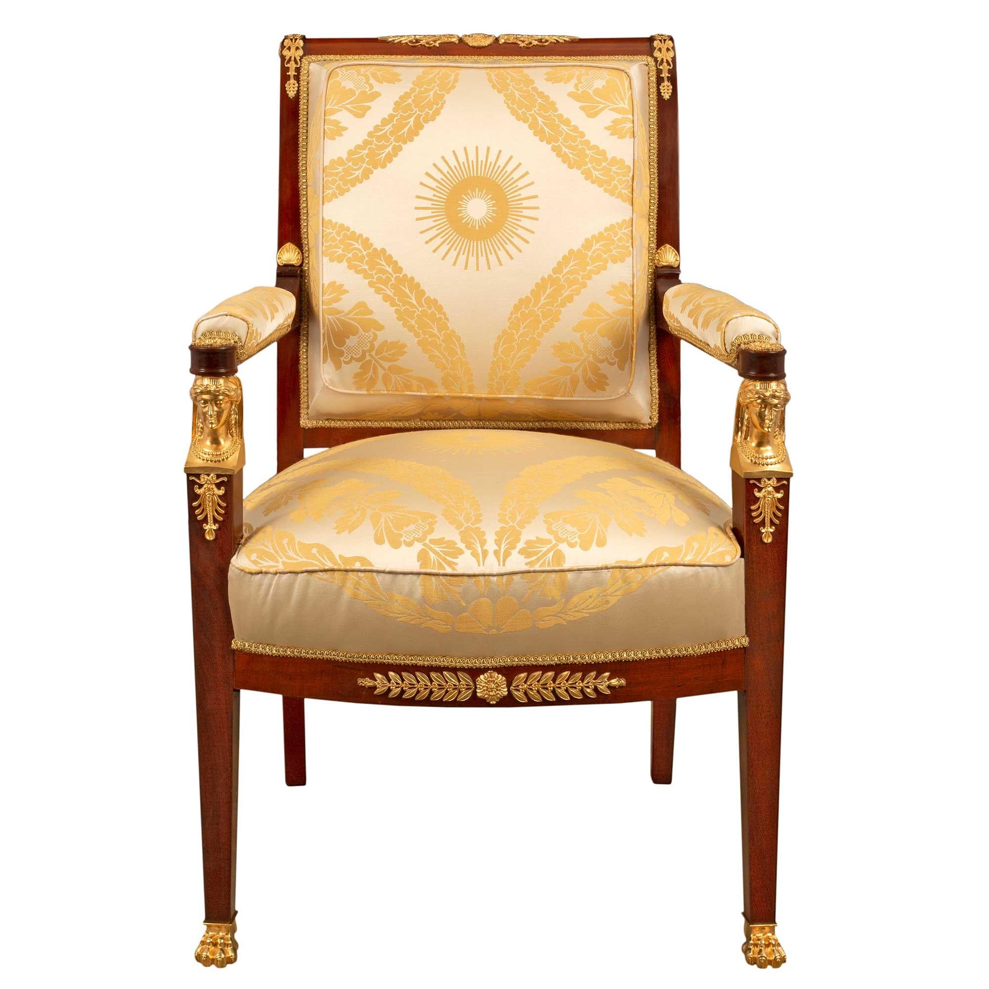 Une très belle paire de fauteuils de style Empire français du milieu du 19e siècle en acajou et bronze doré. La paire est surélevée par des pieds fuselés carrés à l'avant, avec des pieds en bronze doré à pattes et des cariatides exquises et