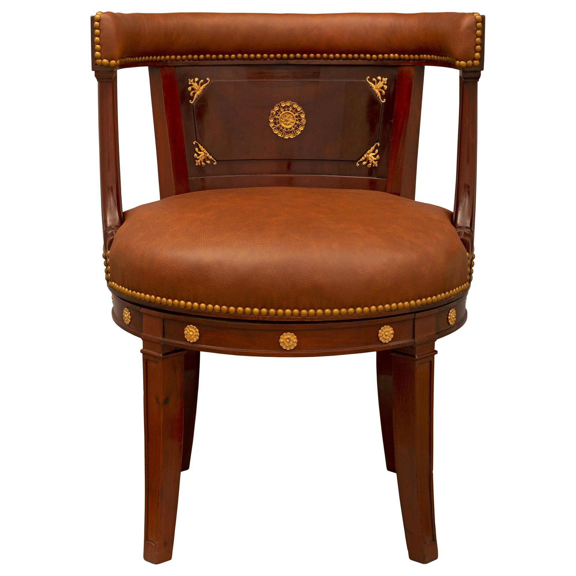 An impressive and unique French 19th century Empire St. Mahogany and Ormolu desk armchair. The armchair is raised by handsome lightly curved square legs with finely carved recessed designs and beautiful finely detailed Ormolu rosettes extending