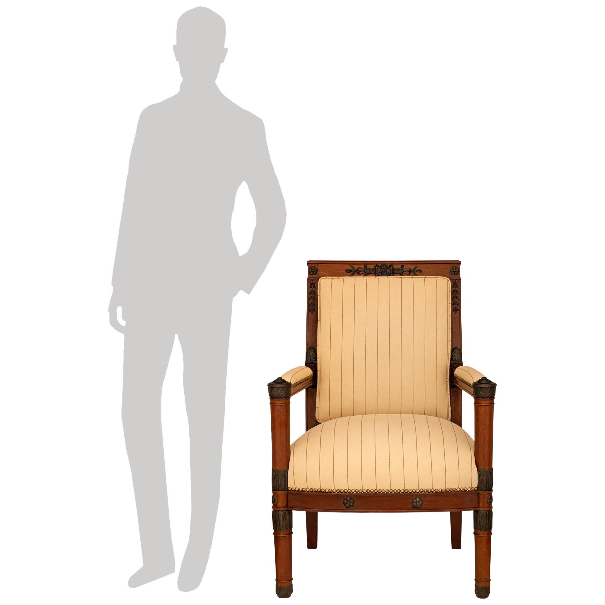 A handsome and high quality set of four French 19th century Empire style Mahogany and patinated Wood armchairs. Each attractive arm chair is raised on four tapered Mahogany legs. The two rounded front legs are decorated by foliate decorations at the