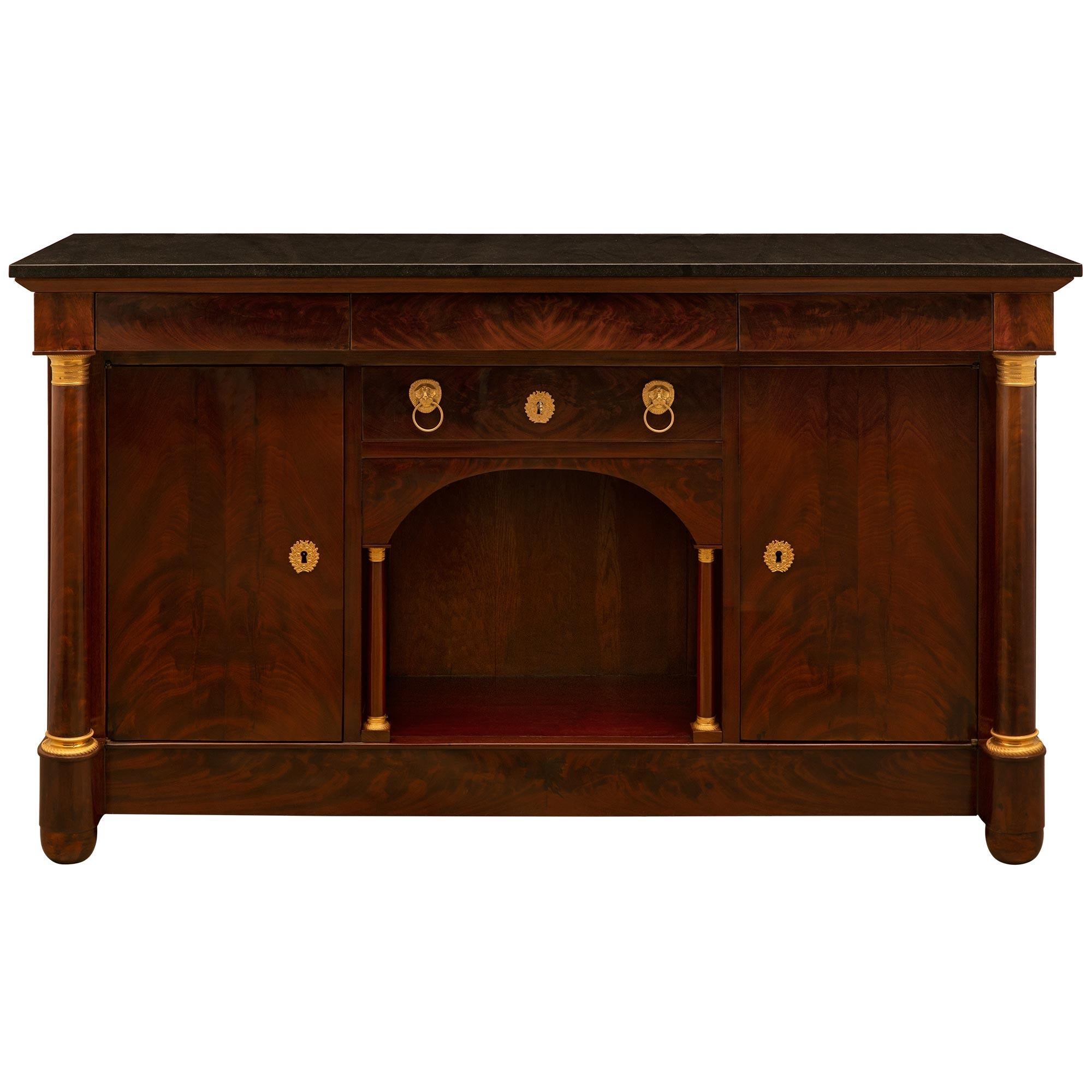 A handsome French 19th century Empire st. Mahogany, Ormolu and marble buffet/cabinet. The buffet is raised on two half round front and two back block supports below the straight apron flanked by circular columns accented with bottom Ormolu plinths