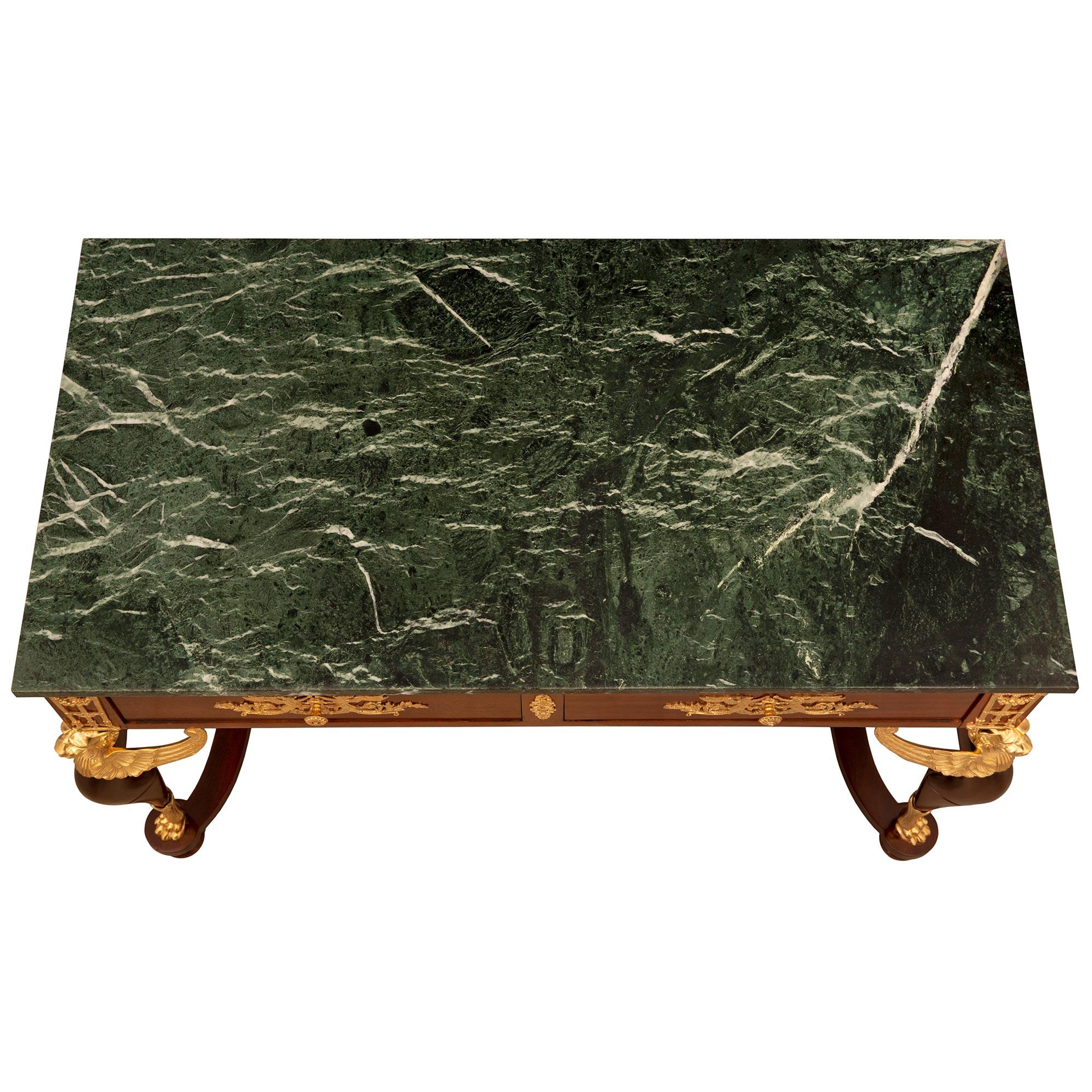 Ein hübscher und beeindruckender französischer Empire-Tisch aus dem 19. Jahrhundert aus Mahagoni, Ormolu und Vert de Patricia-Marmor. Der rechteckige Tisch mit zwei Schubladen wird von geschwungenen, aussagekräftigen Beinen getragen, die ein