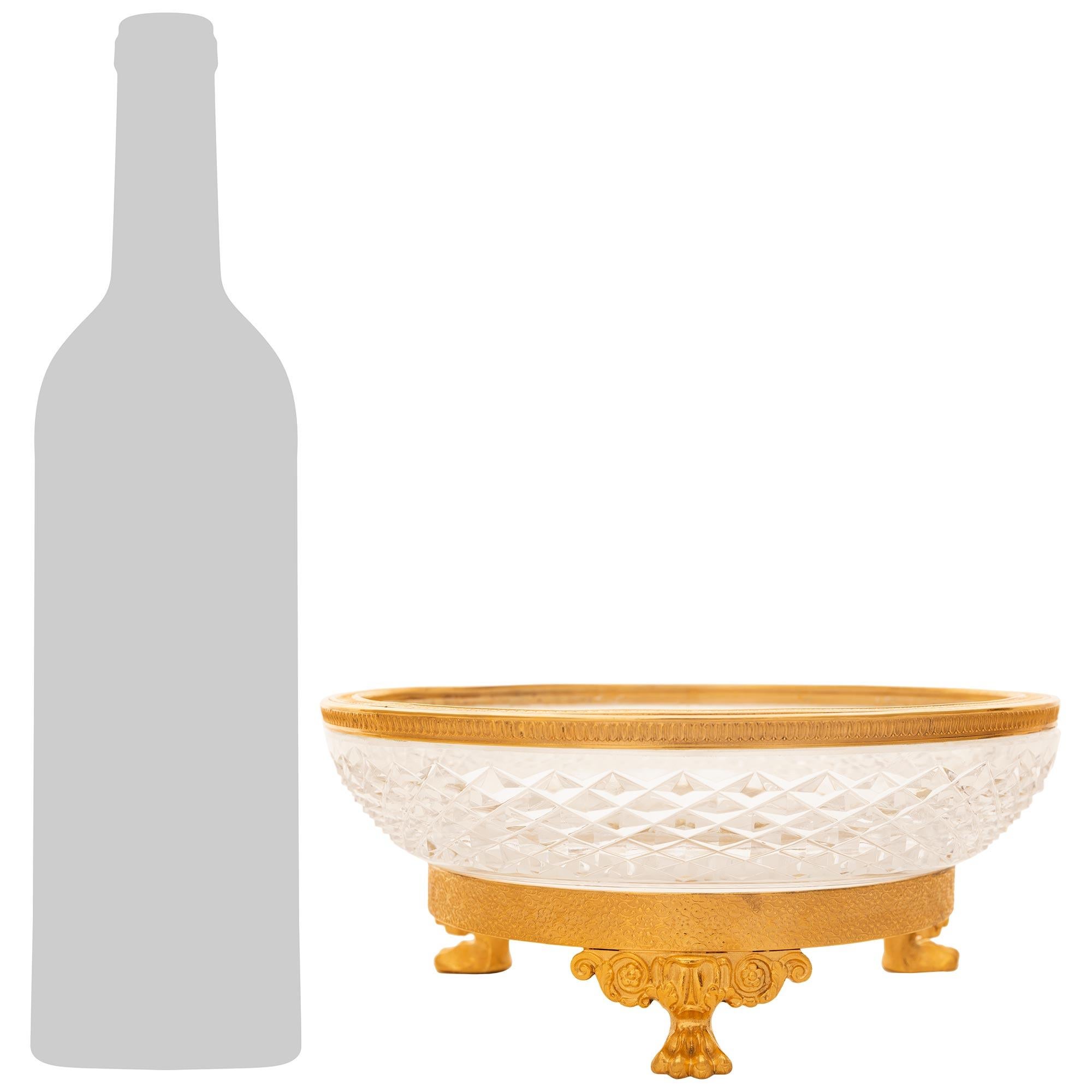Magnifique et très élégant centre de table en bronze doré et cristal de Baccarat de style Empire du XIXe siècle. Cette magnifique pièce centrale est surmontée d'un bandeau circulaire en bronze doré, orné d'un motif de feuillage à volutes complexe,