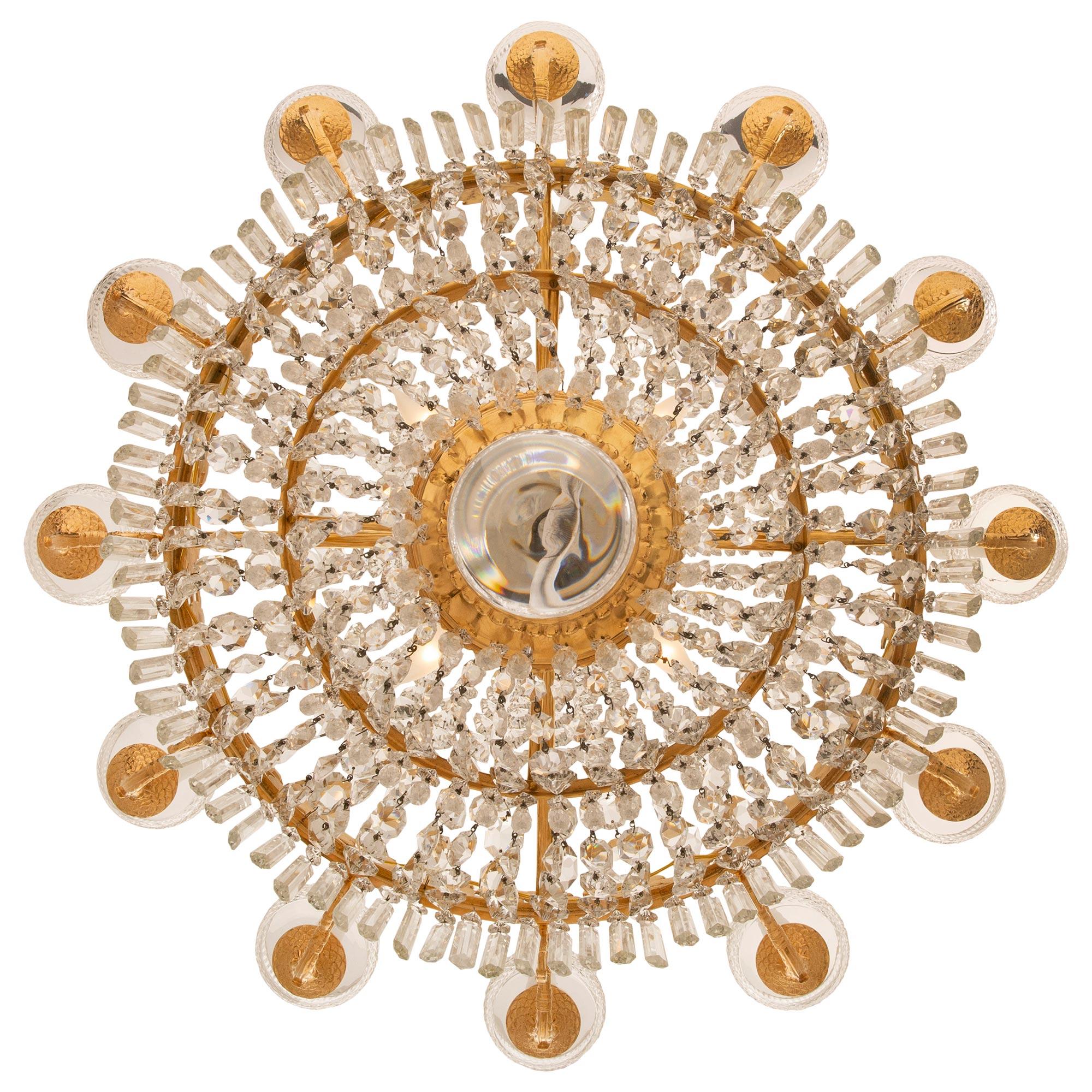 A beautiful and very high quality French 19th century Empire st. ormolu and Baccarat crystal chandelier. The twelve arm sixteen light chandelier is centered by a striking solid crystal ball below the lovely mottled foliate ormolu support with three