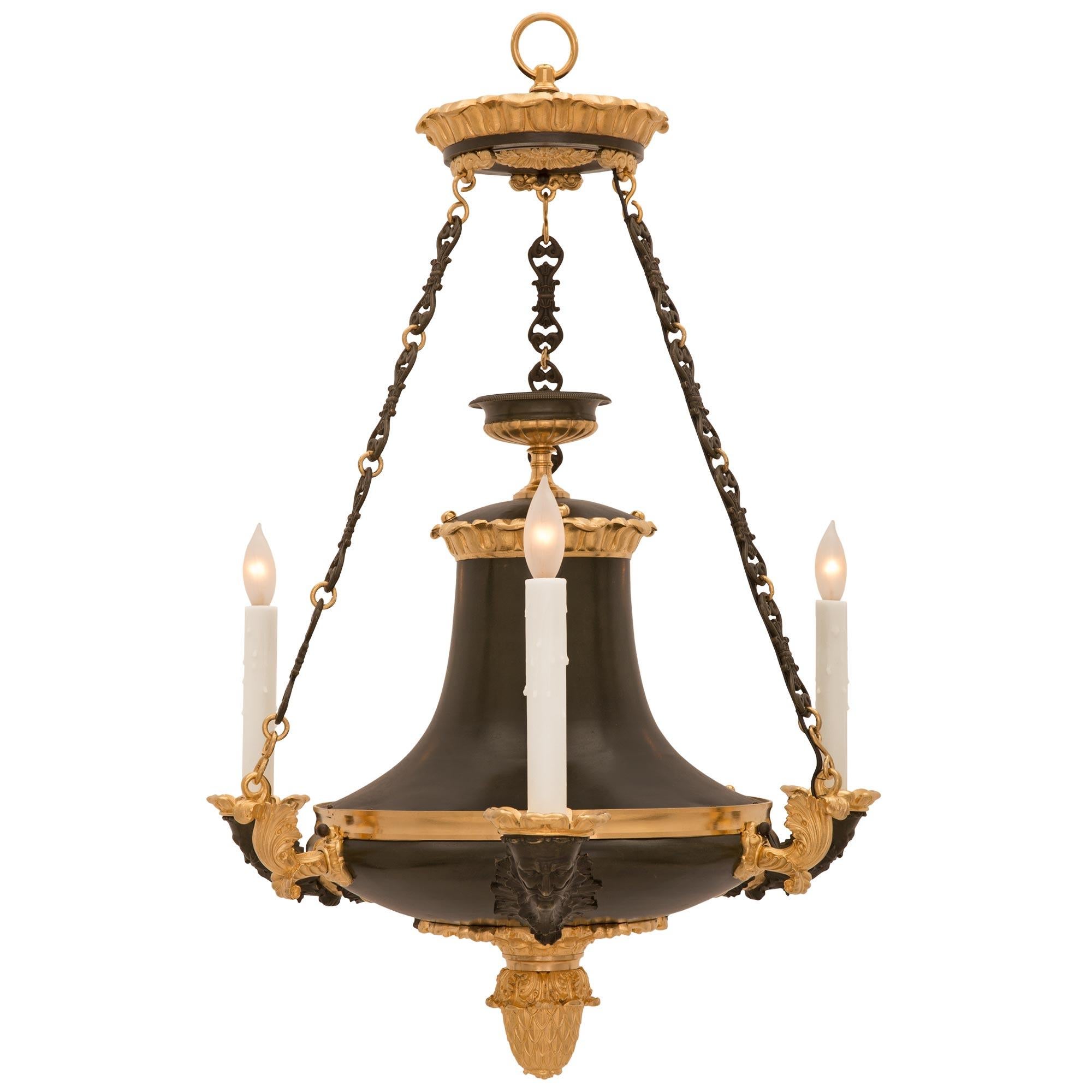 A handsome and high quality French 19th century Empire st. patinated bronze and ormolu chandelier. The three arm chandelier is centered by a beautiful richly chased bottom acorn finial amidst impressive scrolled foliate movements. Each arm displays