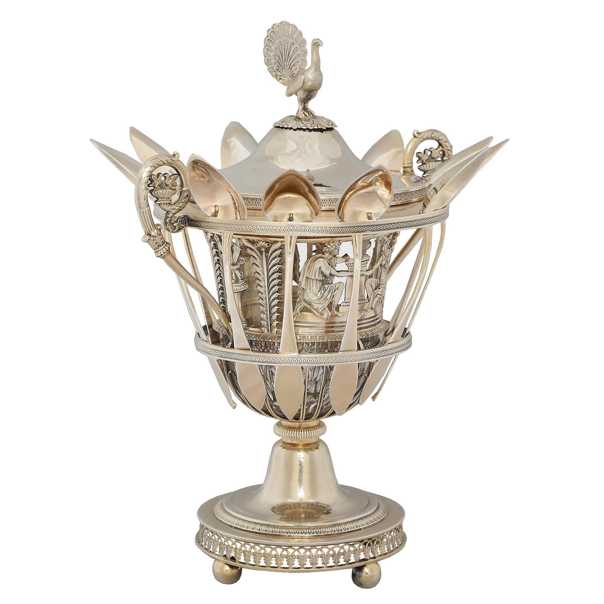 A French 19th century Empire st. sterling silver caviar server. This ornate server is raised on a round base with a pierced foliate pattern. Richly chased male and female figures in garments of the day alternating with the flame of eternity between