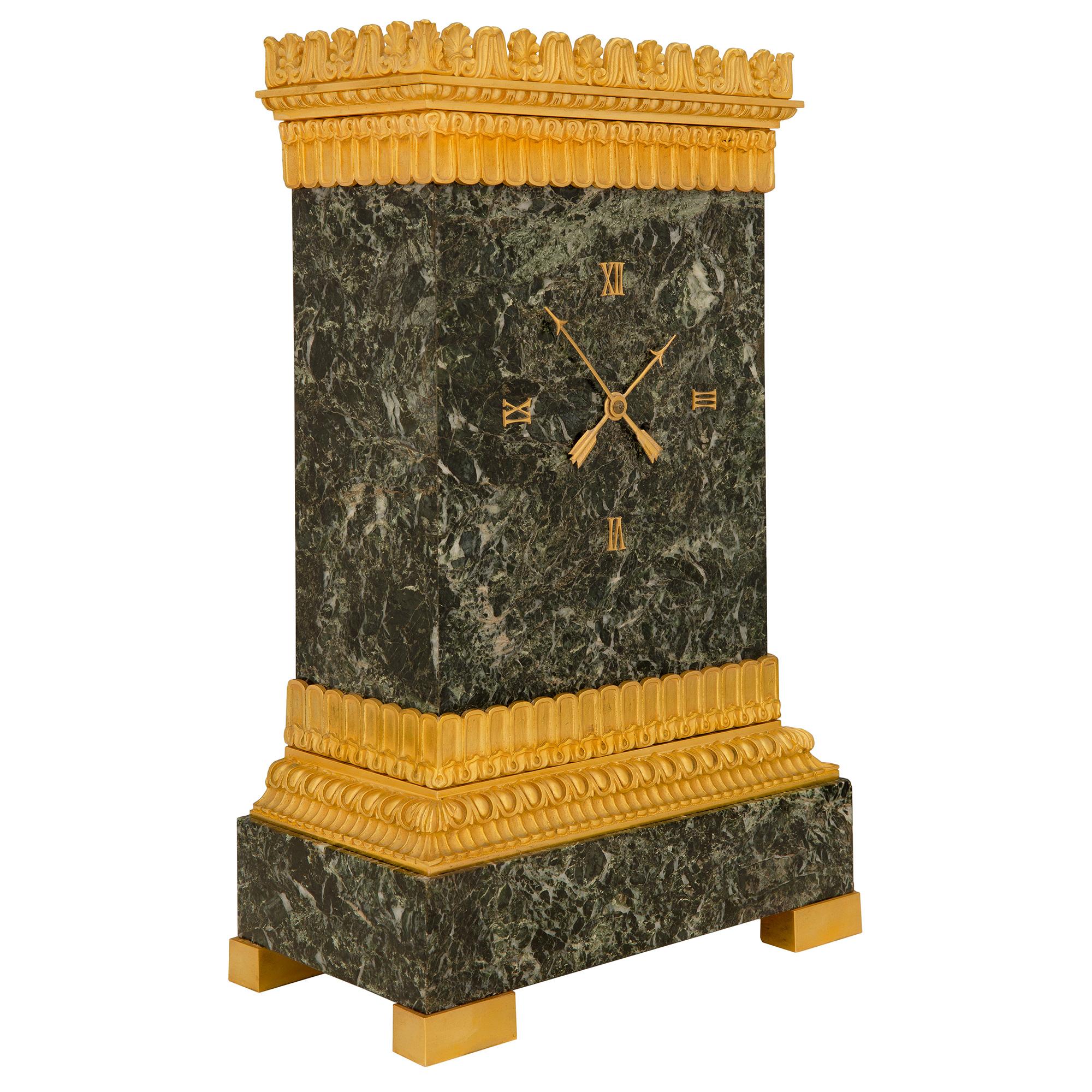 Une belle horloge française du 19ème siècle, de style Empire, en marbre Vert Patricia et ormolu. La pendule est surélevée par de fins supports rectangulaires en bronze doré sous le socle en marbre Vert de Patricia. Un étonnant bandeau en bronze doré