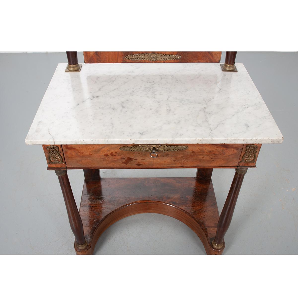 This exceptional mahogany dressing table is complete with its original mercury glass pivoting mirror and white marble top. The mirror has foxing and is framed with beautiful mahogany trim with brass ormolu details across the top and bottom. It is