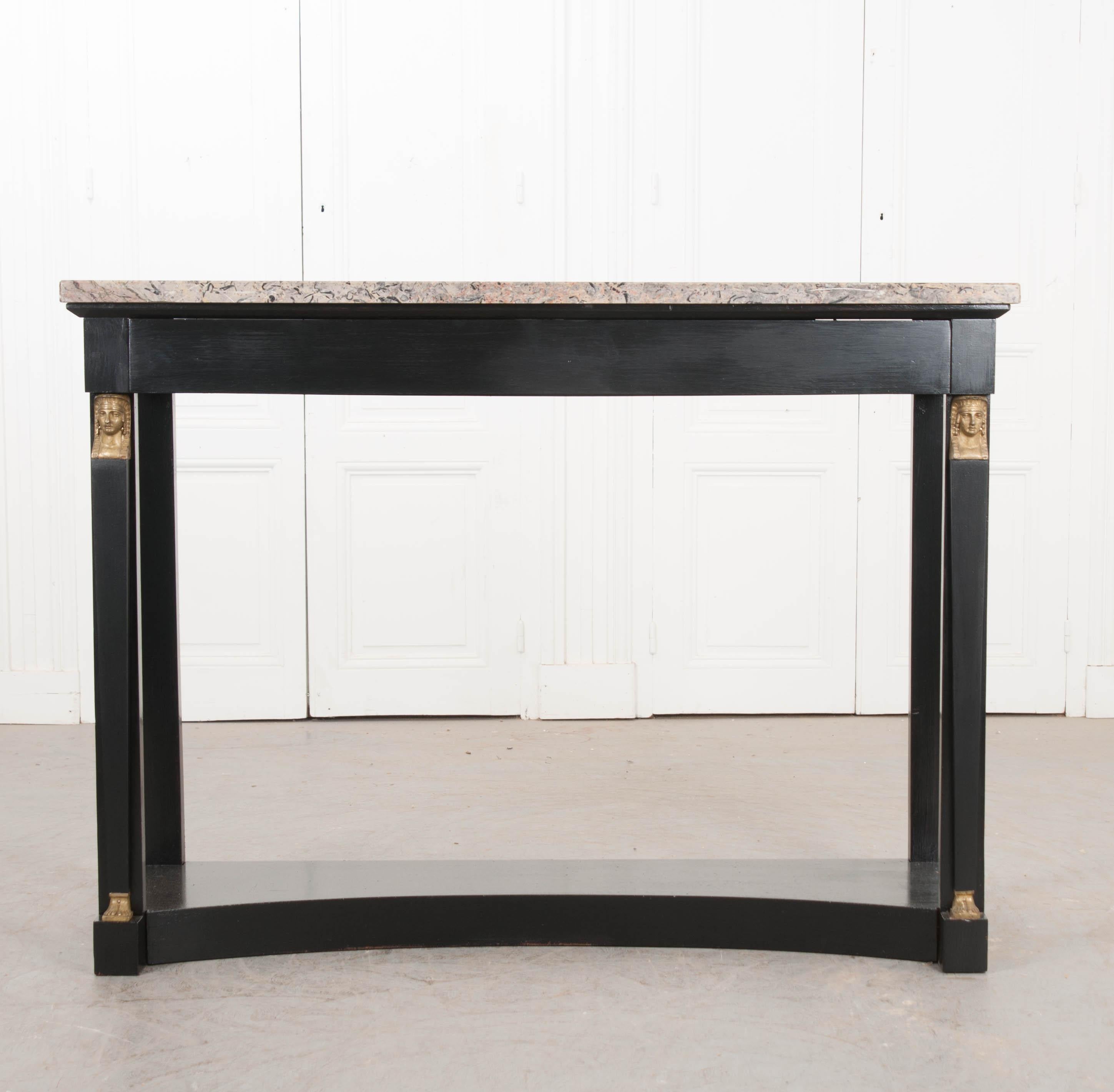 This Classic Empire-style ebonized and marble-top console table, circa 1870, is from France. The beautiful marble top includes shades of grey, beige, rose, and black. Highlighting the clean lines of this console are female gilt brass terms. Of