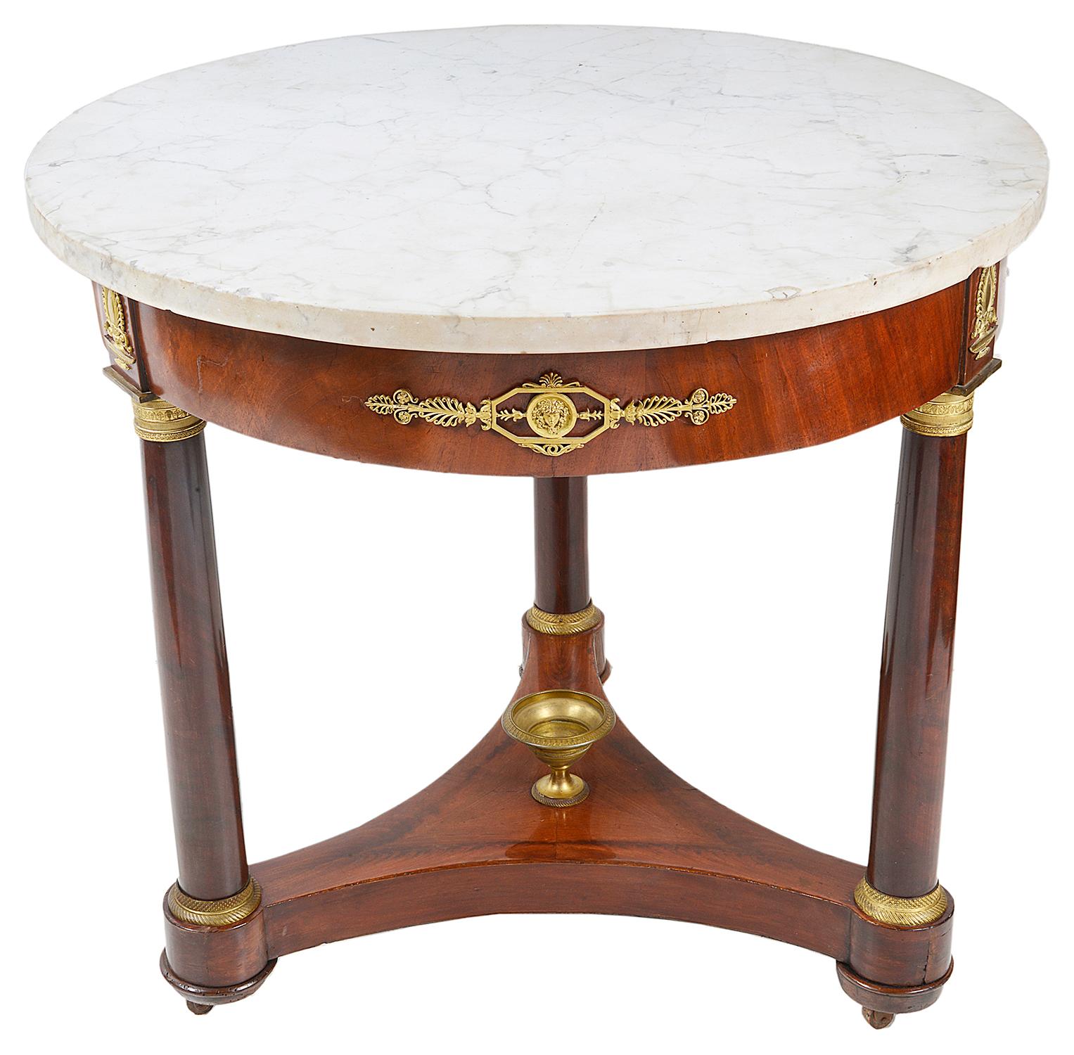 A good quality 19th Century French mahogany marble topped Gueridon, having three circular tapering column supports, each with gilded ormolu capitals and classical ormolu motifs to the frieze, the triform stretcher beneath having a gilded ormolu urn