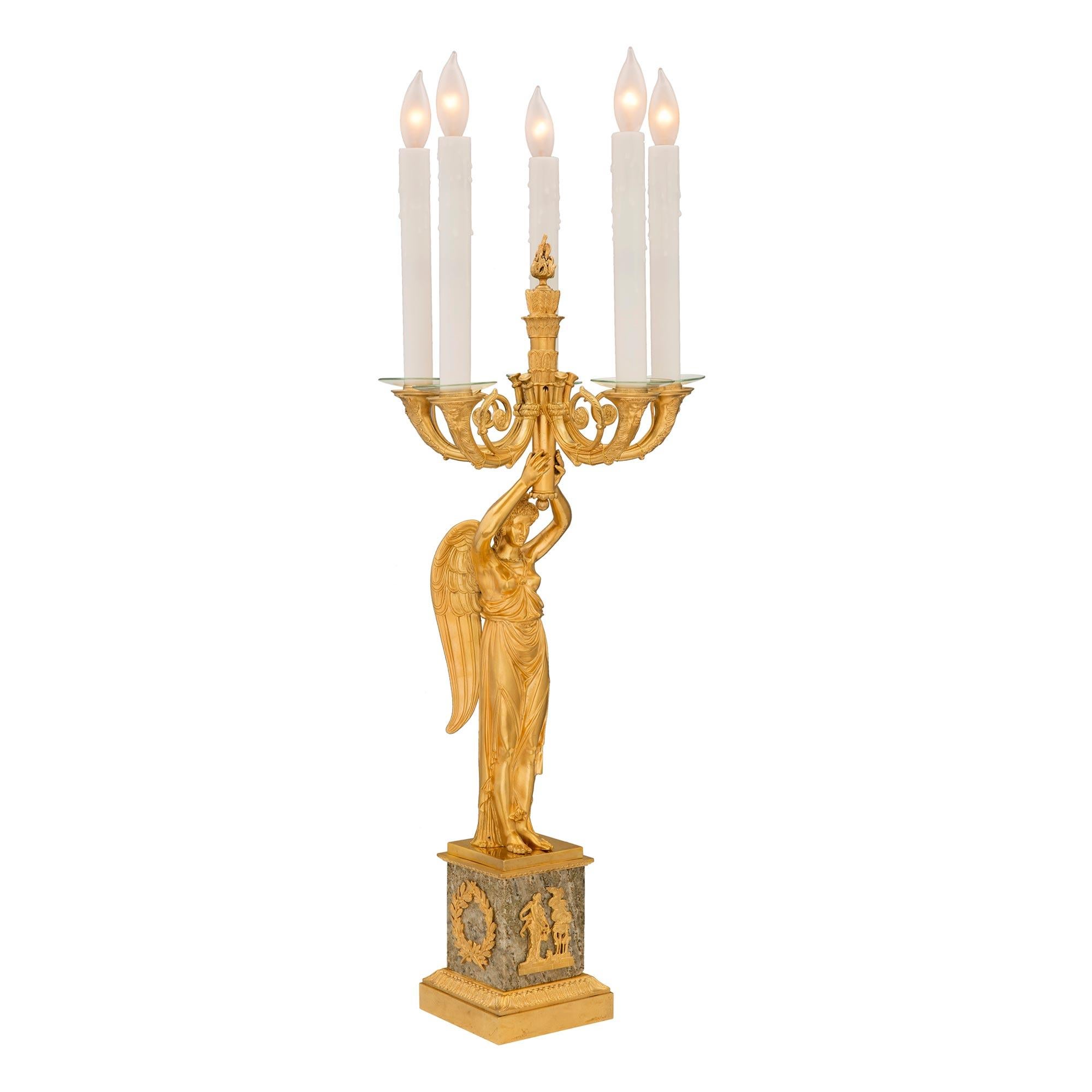 An exquisite true pair of French 19th century Empire st. ormolu and granite five arm lamps, after a model by Claude Galle. Each lamp is raised by a square granite base with a beautiful stepped ormolu foliate wrap around band and richly chased laurel