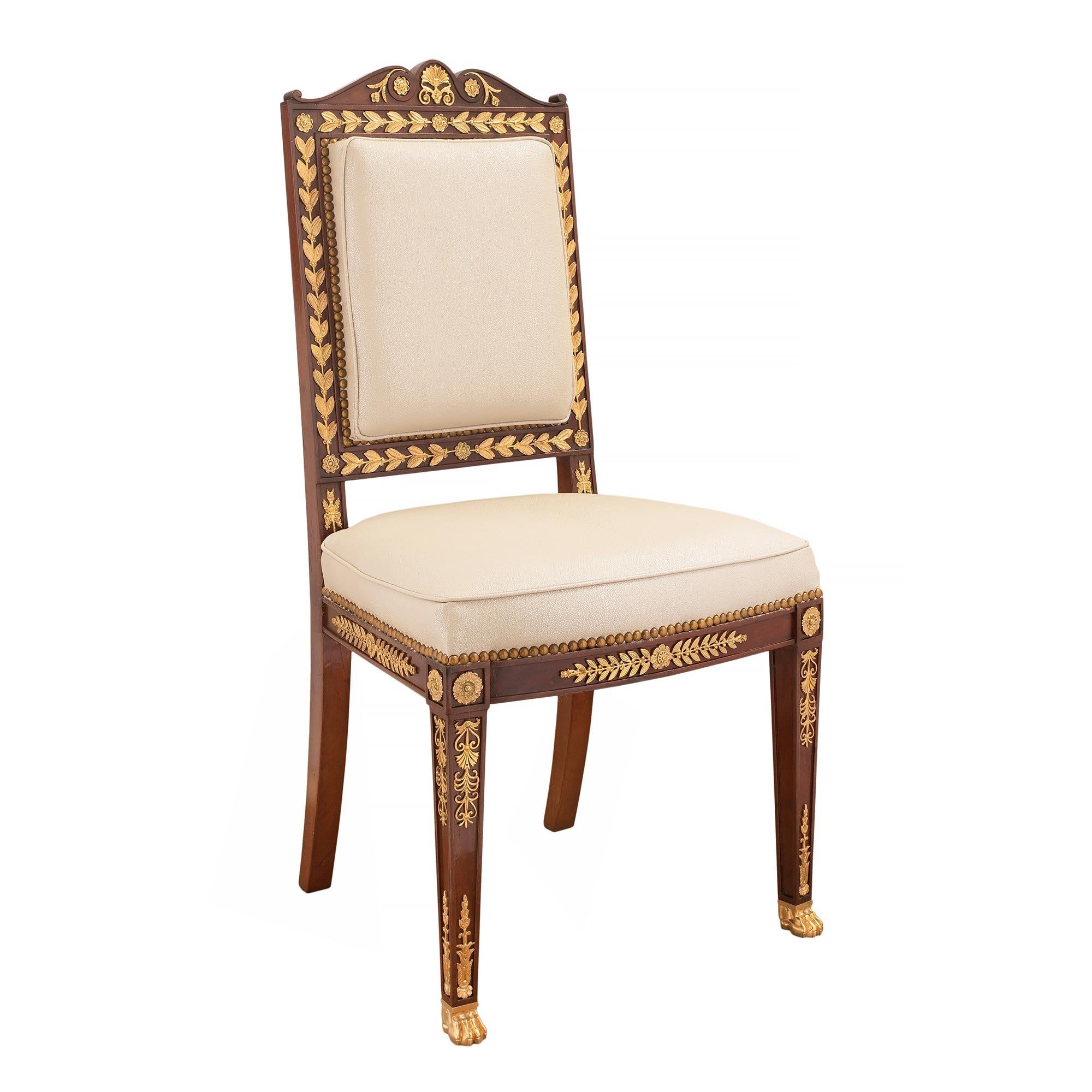 A striking French 19th century Empire st. ormolu and solid mahogany side chair. The chair is raised by handsome ormolu paw feet and square tapered legs. Each leg is accented with decorative recessed panels with intricately chased fitted pierced