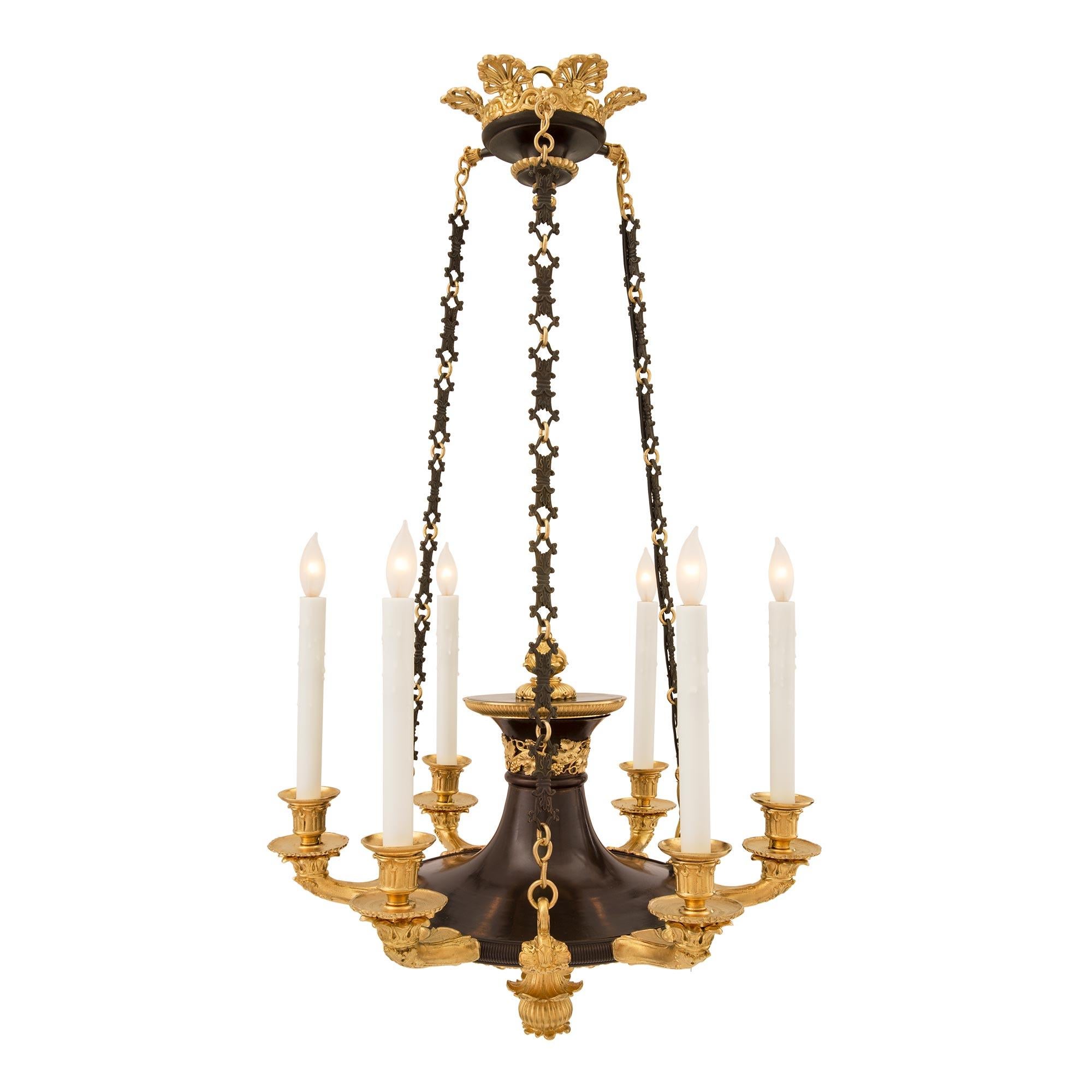 A handsome French 19th century Empire st. patinated bronze and ormolu six arm chandelier. The chandelier is centered by a richly chased ormolu bottom finial amidst decorative foliate designs. The elegantly curved patinated bronze body displays an