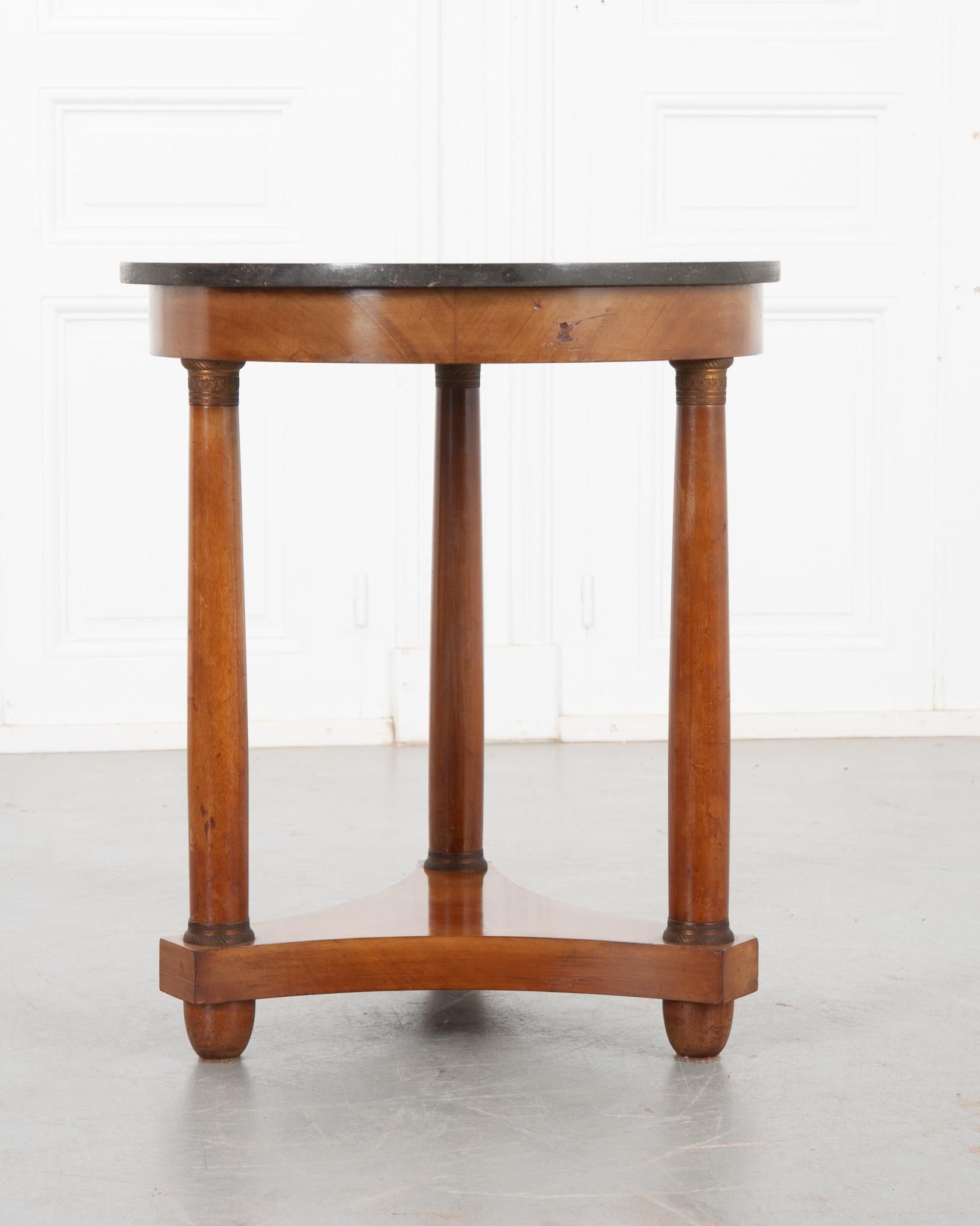 This wonderful 19th century Empire table is the perfect addition to any home decor style. Beautiful, black Belgian granite - in great condition - tops the rich mahogany base. Three turned column-form legs lift the top, each with highly decorative