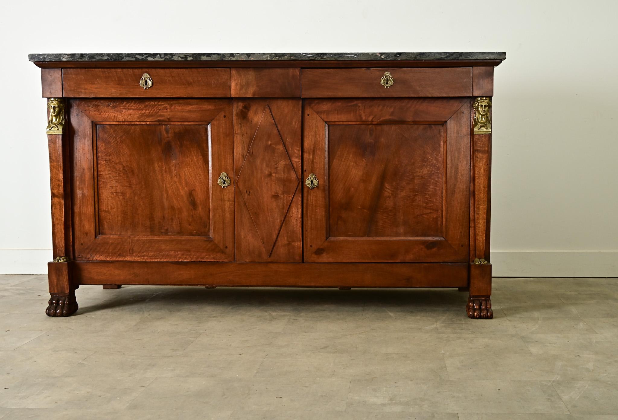 Un buffet monumentale in stile Impero francese, realizzato in noce scolpito in una ricca tonalità ramata, che si coordina con la superficie del piano in marmo scuro per un look classico e neoclassico. La lastra di marmo originale mostra sacche di