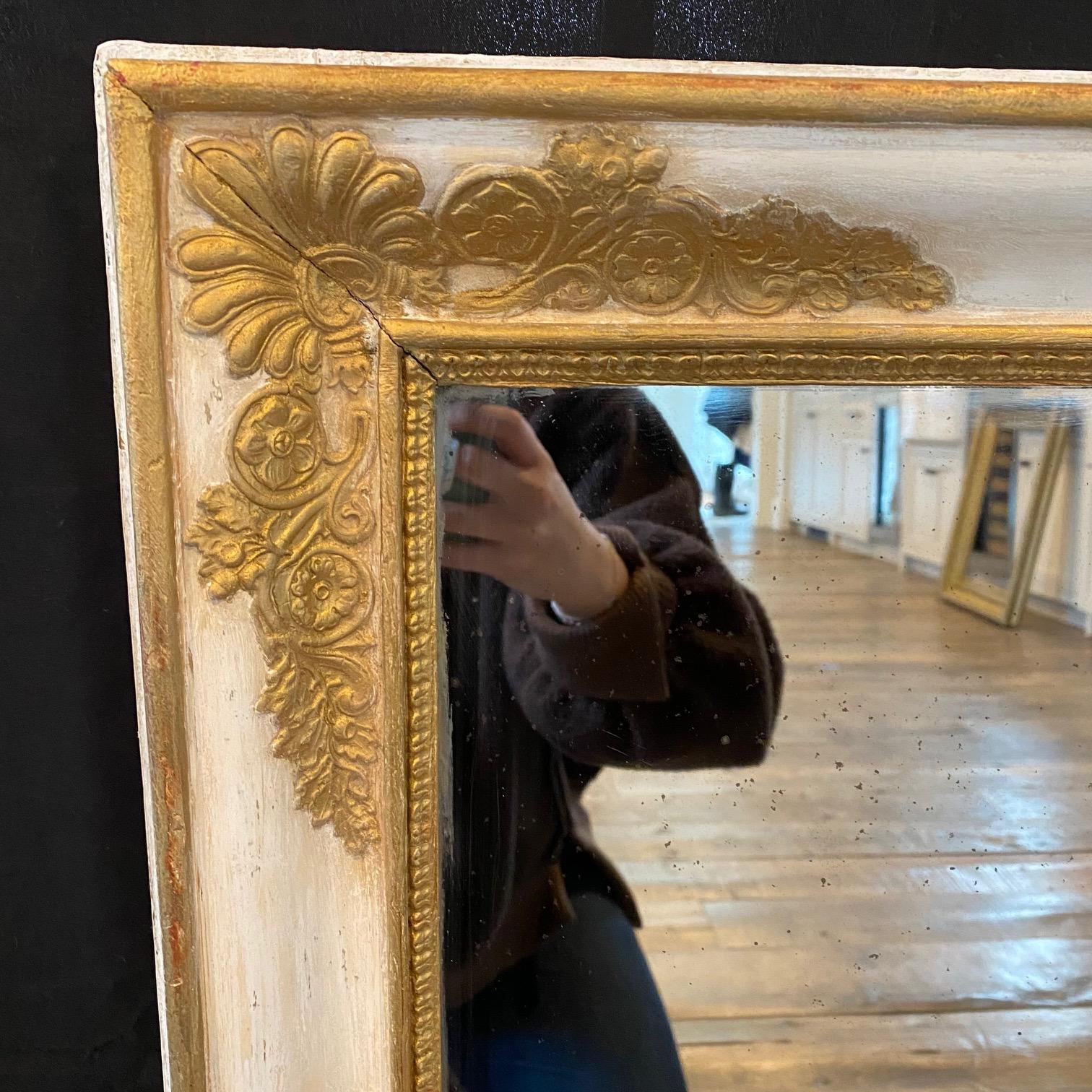 Bellissimo specchio Eleg in oro, dorato e avorio, che rappresenta un elegante elemento di spicco. La finitura in legno dorato è completata da un'incantevole patina di gesso bianco dipinto all'inizio,  e il motivo neoclassico in rilievo è un classico