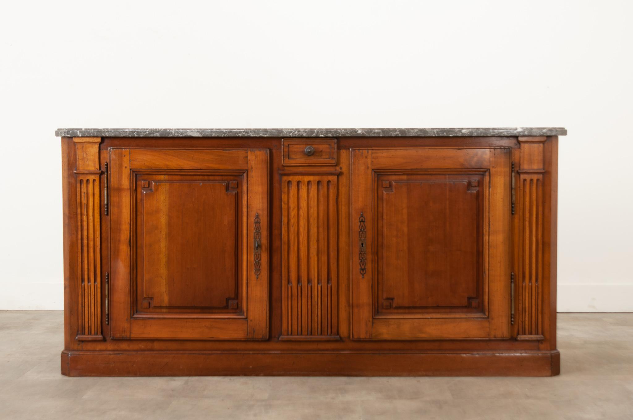 A beautiful fruitwood transitional enfilade circa 1870. The original shaped, canted marble top is gray with beautiful white veining throughout. Just below the marble top is a small drawer that opens and closes with ease.  Fluted columns flank two