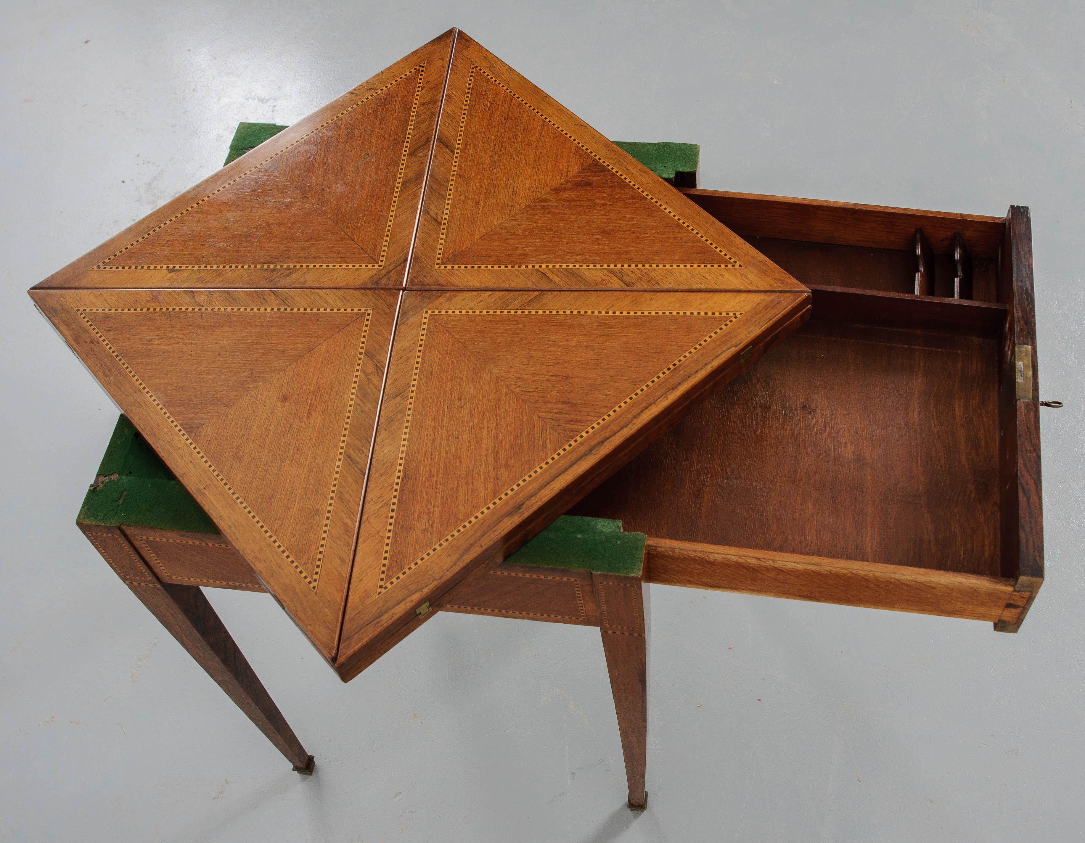 The mixed wood of mahogany, rosewood, satinwood and ebony wood envelope game table has 4 folding panels that extend the table from 21-?” W to 30-?” W. Just twist the table top to get one of the center corners to pop up and fold out the four panels.