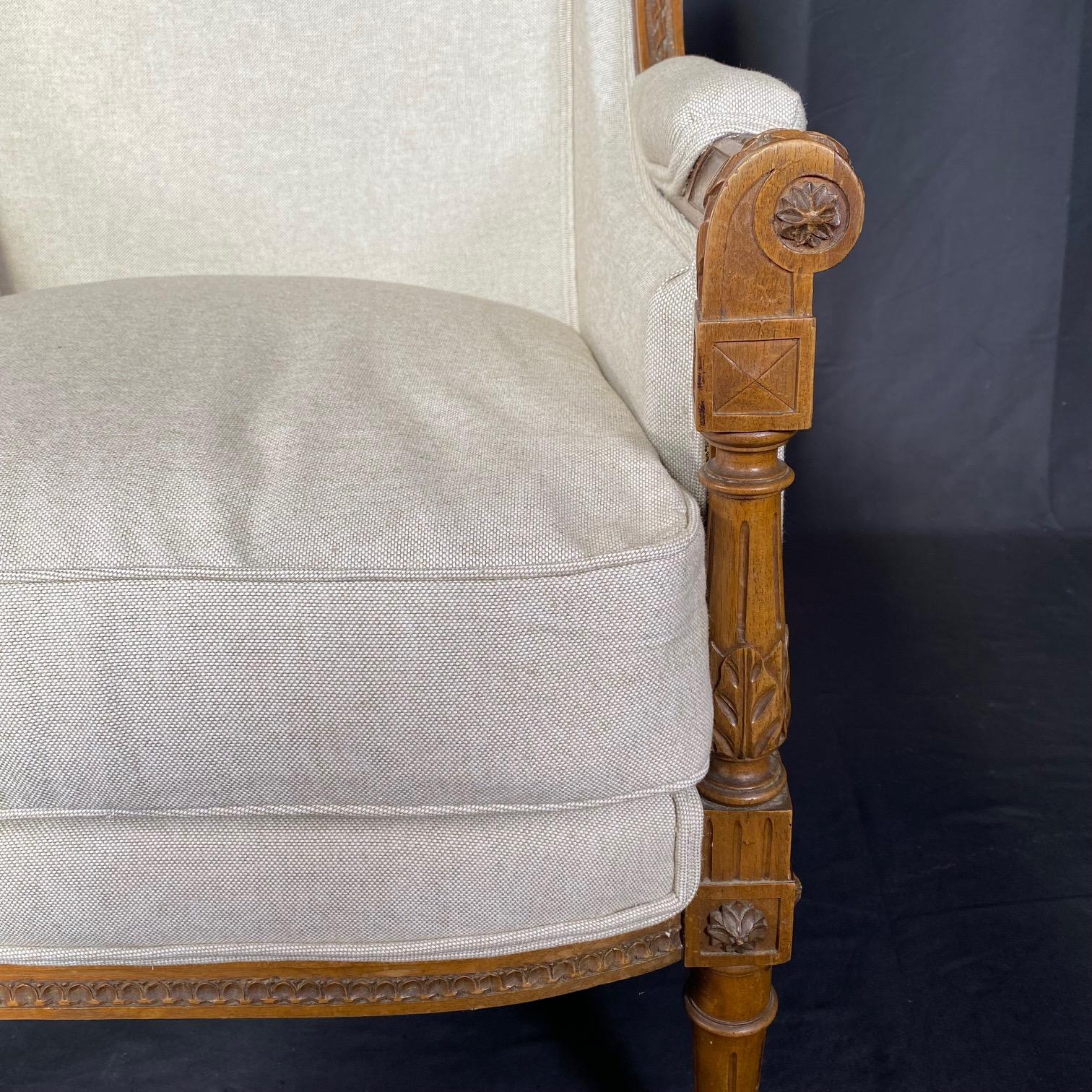Exquisite French 19th Century Louis XVI elegant and comfortable finely carved walnut armchair bergere chair with new high end British upholstery. Will add a touch of class and sophistication to any room in the home! Wonderful living room or bedroom